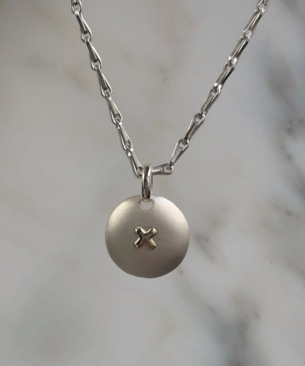 Close-up of Limited Edition Sapphire Disc Pendant with engraved kiss and Brushed Silver