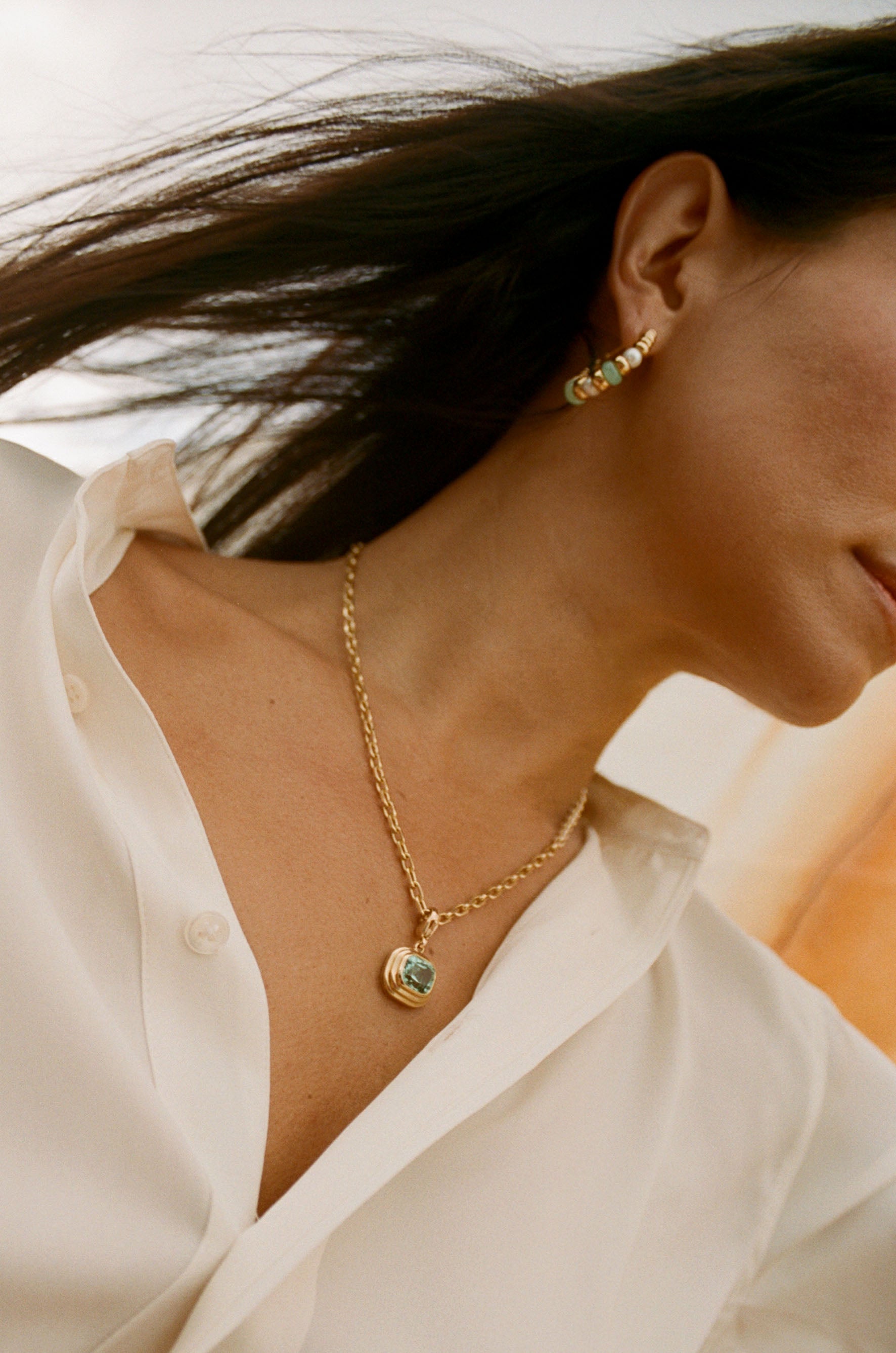 Model wearing Athena collection necklace in 18k yellow gold with cushion-cut blue Tourmaline pendant