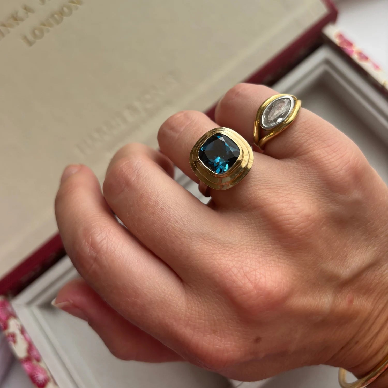 Hand wearing Athena 4ct London blue topaz ring in 14k yellow gold and sterling silver with cushion-cut deep blue topaz