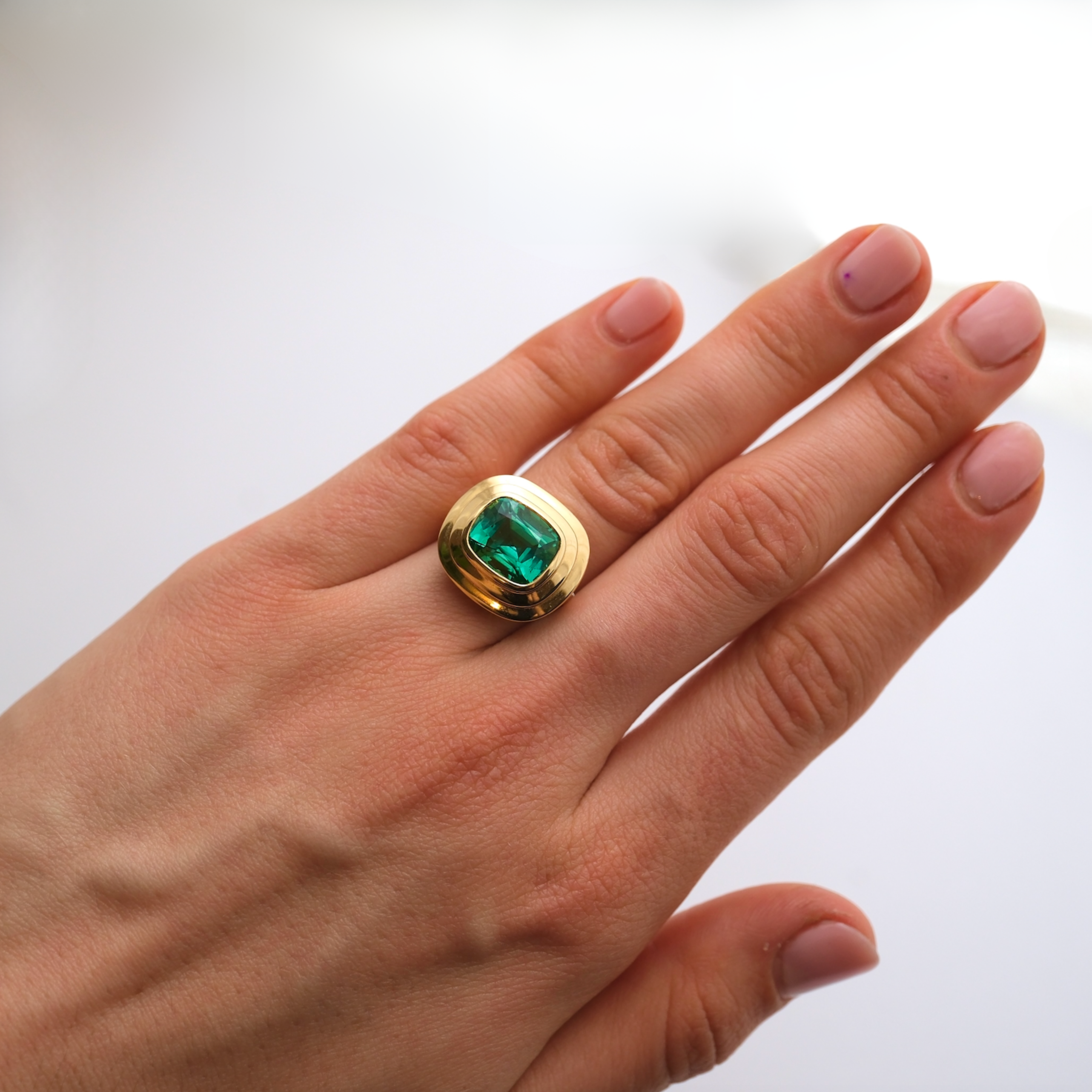 Hand model wearing Athena collection 18k yellow gold ring with 4.80ct intense blue-green cushion-cut Tourmaline