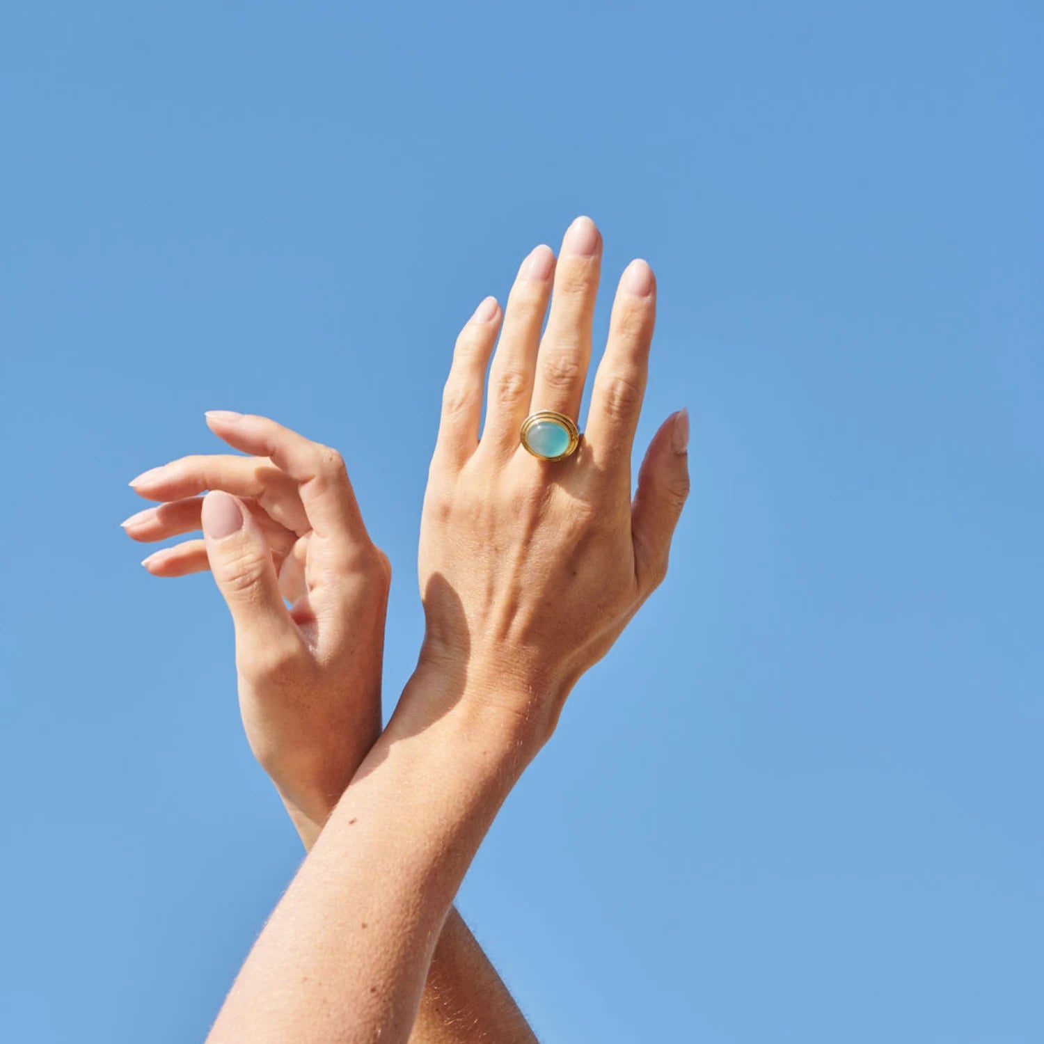Hand model wearing Athena sea blue chalcedony cabochon ring in 18k yellow gold with 14x12mm one-of-a-kind gemstone