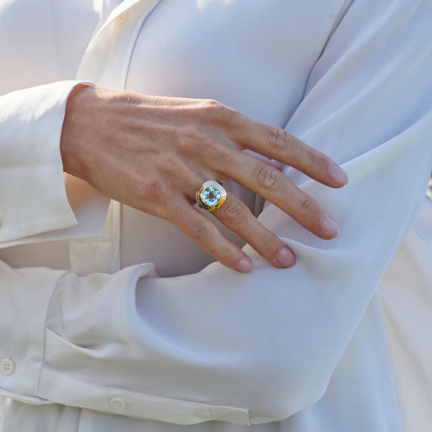 Model wearing Athena 4ct sky blue topaz ring in 14k yellow gold and sterling silver with cushion-cut topaz