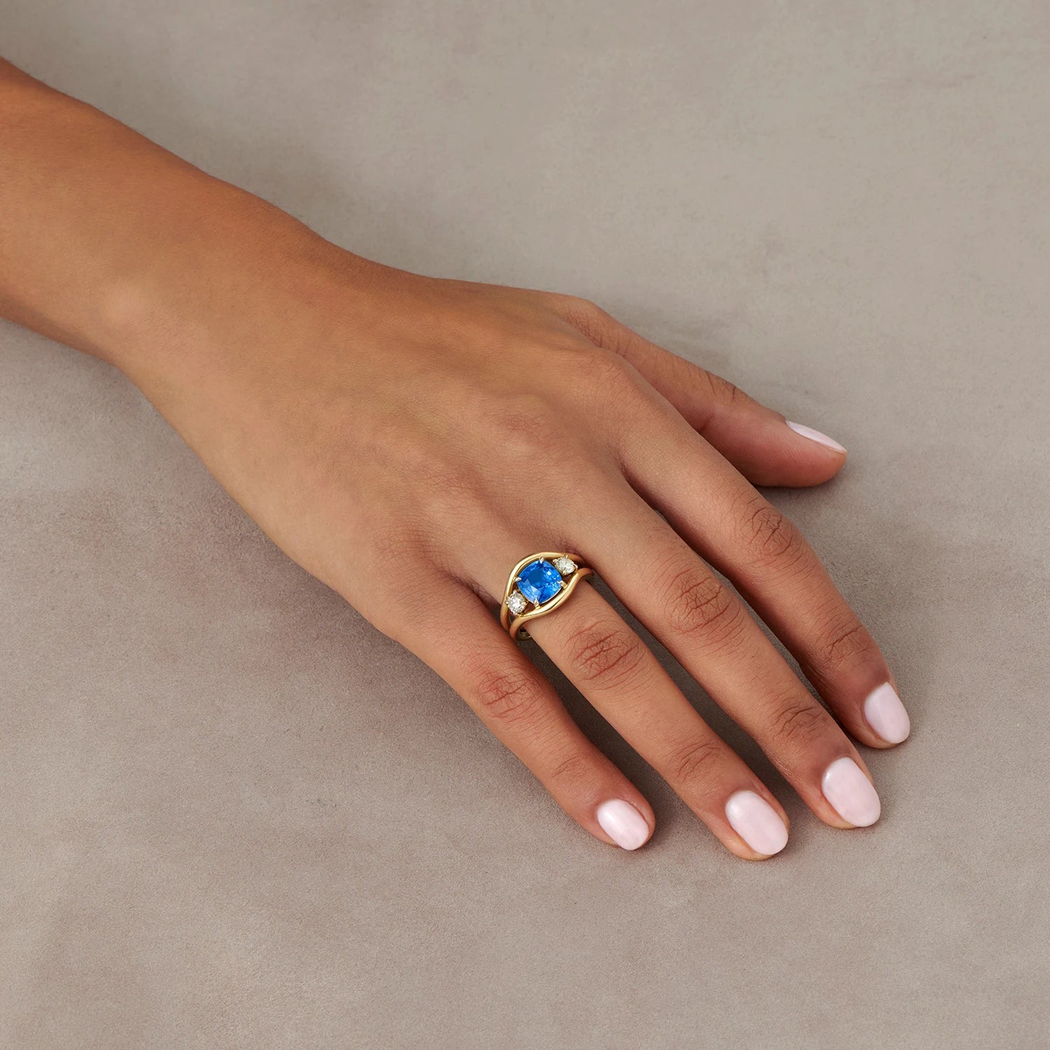 Hand model wearing Atlantis mermaid ring with 2.72ct cornflower blue sapphire and 0.50ct white diamonds in 18k yellow gold