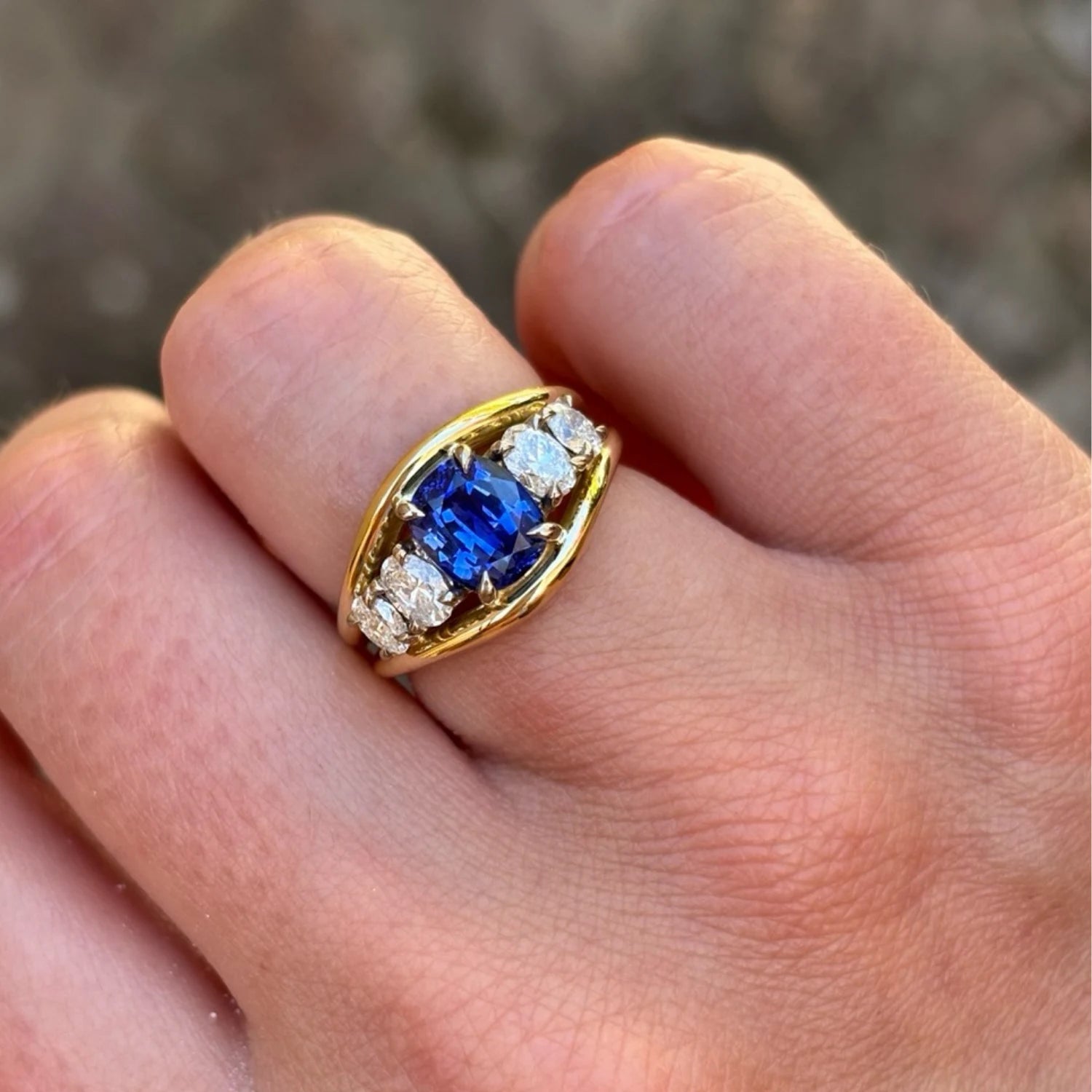 Hand wearing Atlantis sapphire and diamond mermaid ring in 18k yellow gold with 3.04ct royal blue sapphire and oval-cut white diamonds