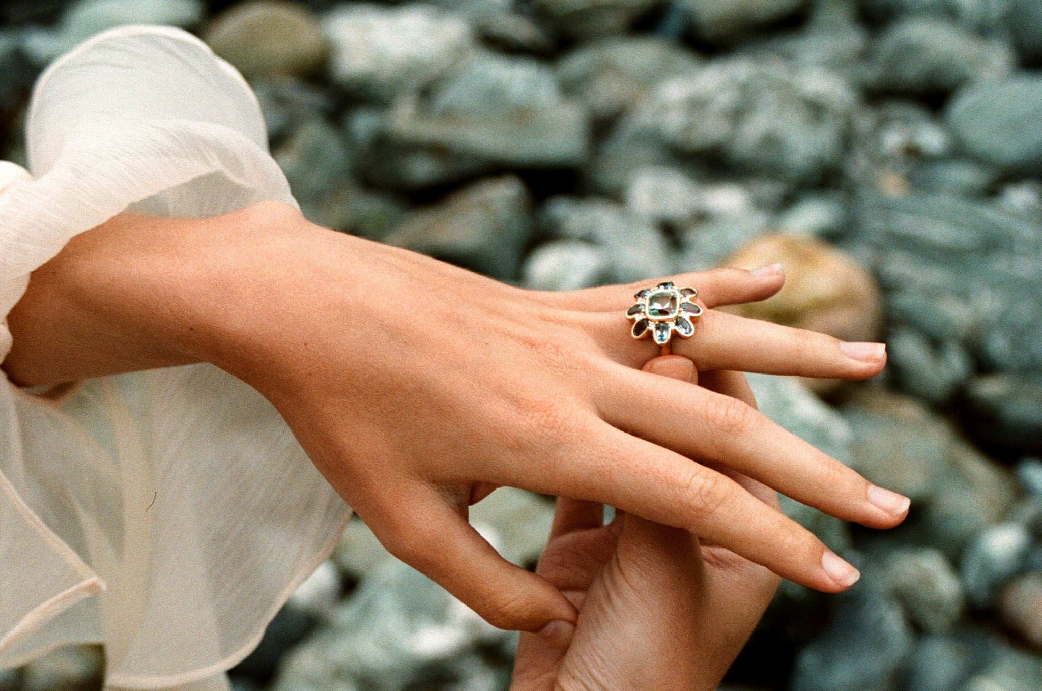 Hand model wearing Atlantis collection 18k yellow gold ring featuring 5.30ct green Tourmaline, 3.39ct Aquamarine, and diamonds