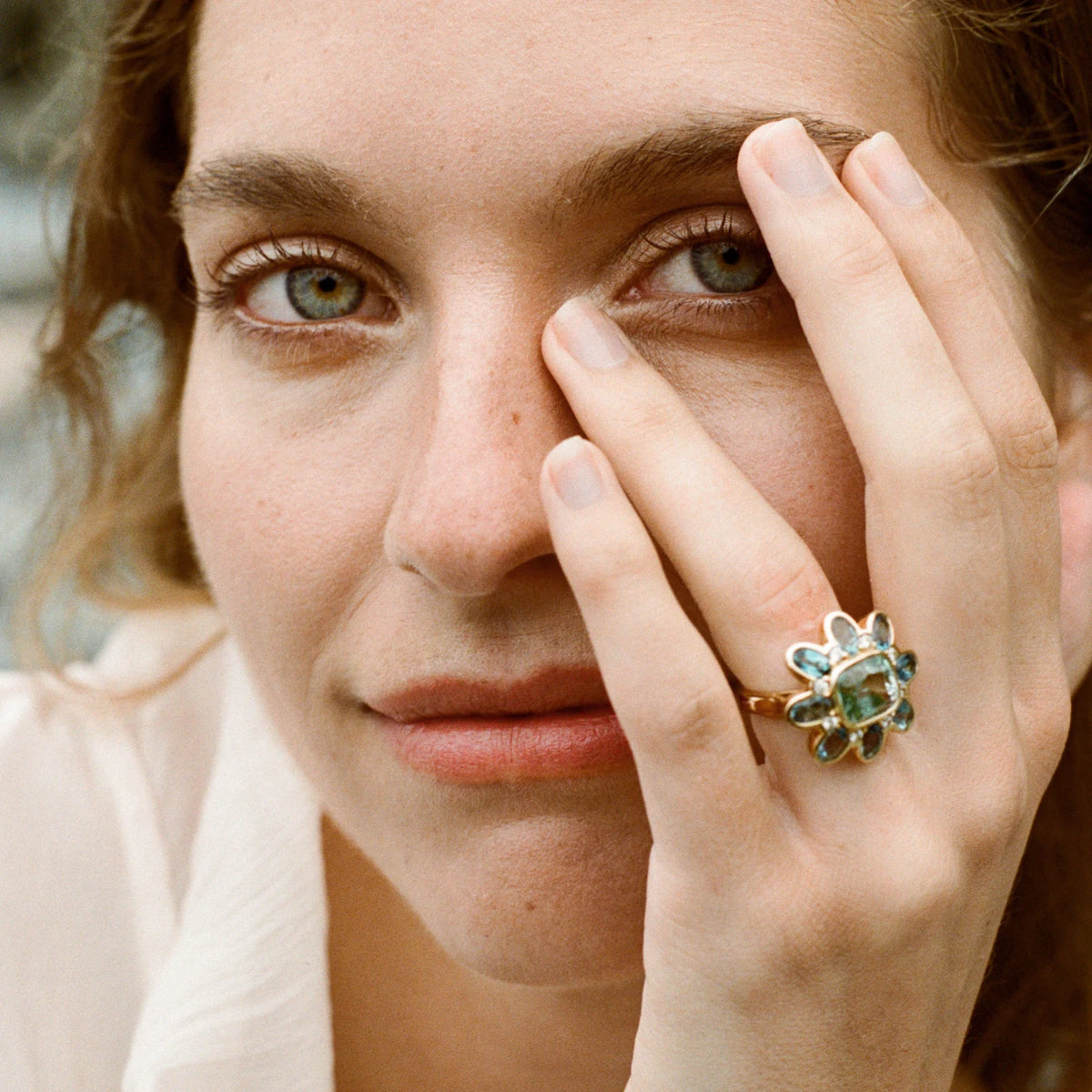 Model wearing Atlantis Tourmaline, Aquamarine, and Diamond ring on model’s hand, handcrafted in 18k yellow gold, featuring 5.30ct ocean green tourmaline, 3.39ct Santa Maria aquamarines, and 0.32ct diamonds, ocean-inspired design