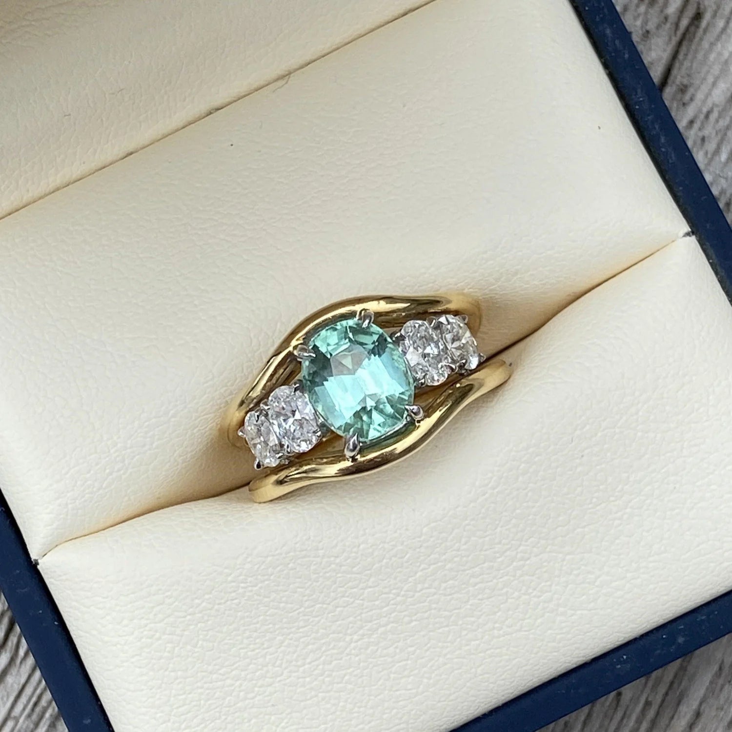 Atlantis green tourmaline and diamond ring in 18k yellow gold with oval-cut white diamonds displayed in a jewellery box