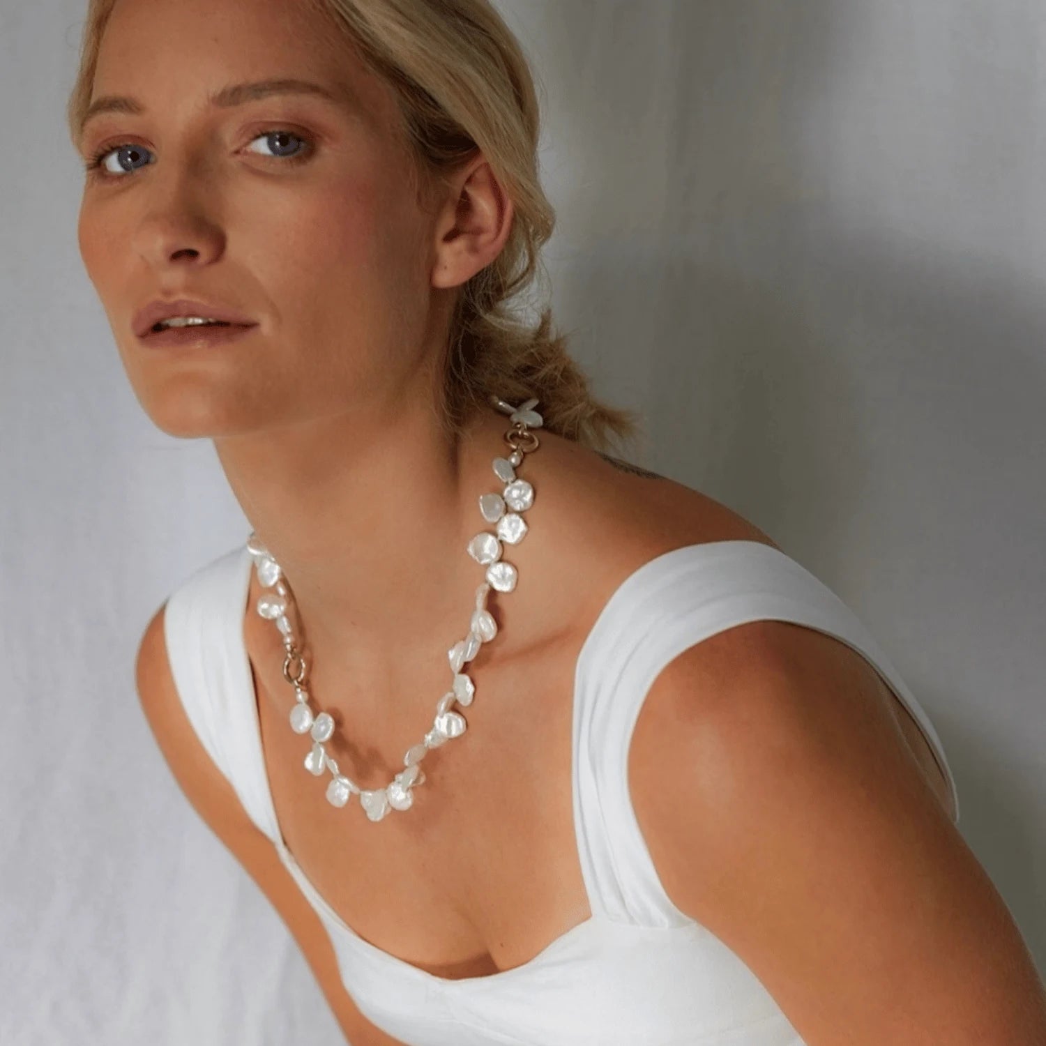 Model wearing Atlantis collection 18k yellow gold necklace featuring white Keshi pearls