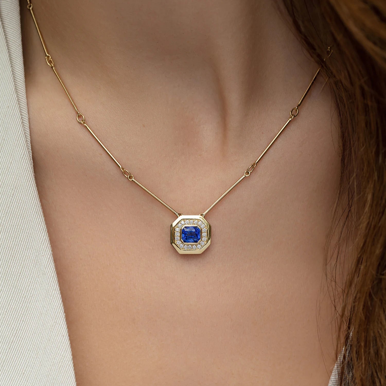 Model wearing Berlin Nights Blue Sapphire Necklace, 18k gold with 2.10ct square octagonal-cut sapphire and diamond halo pendant.