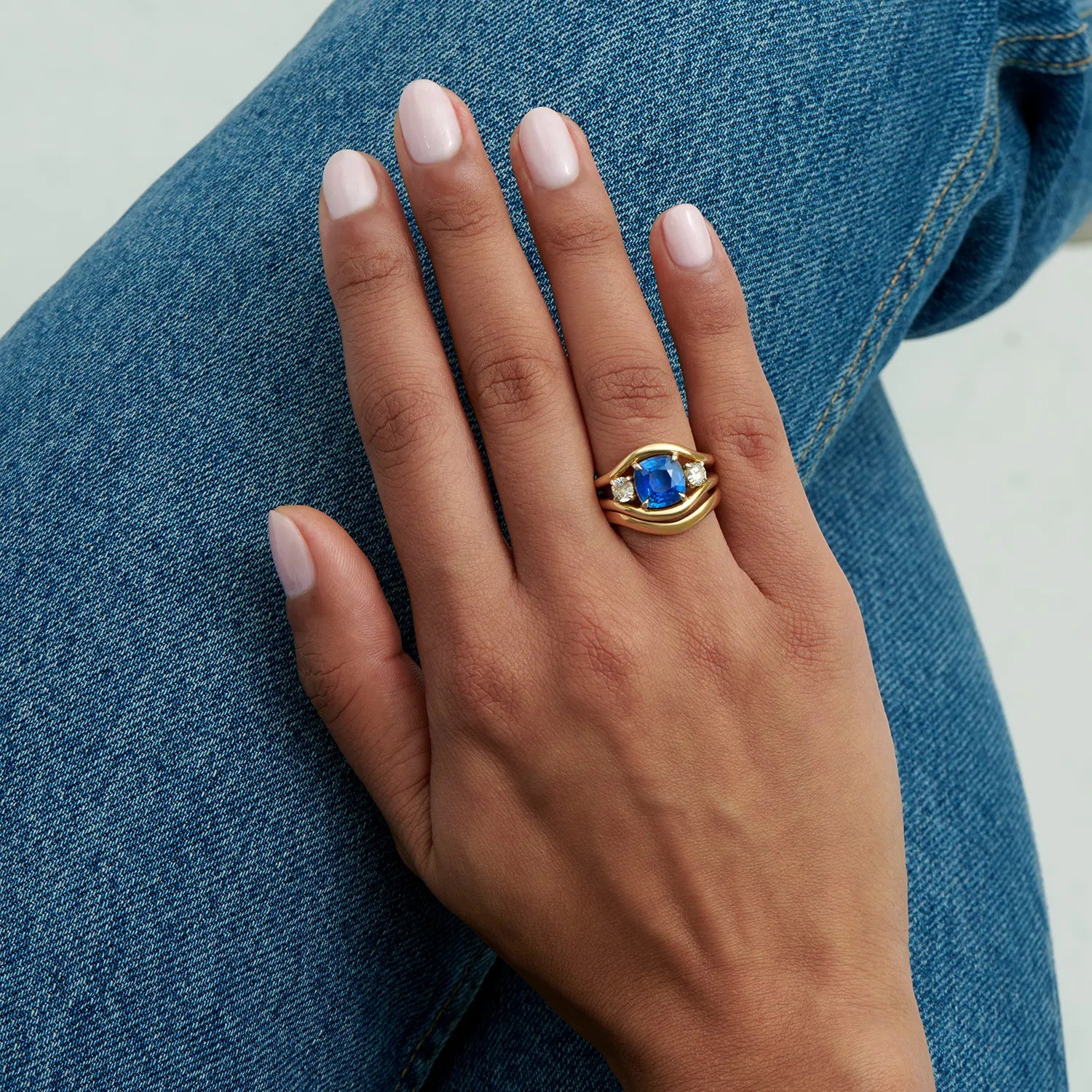 Atlantis curved wedding band in 18k yellow gold styled with sapphire engagement ring for a harmonious bridal stack