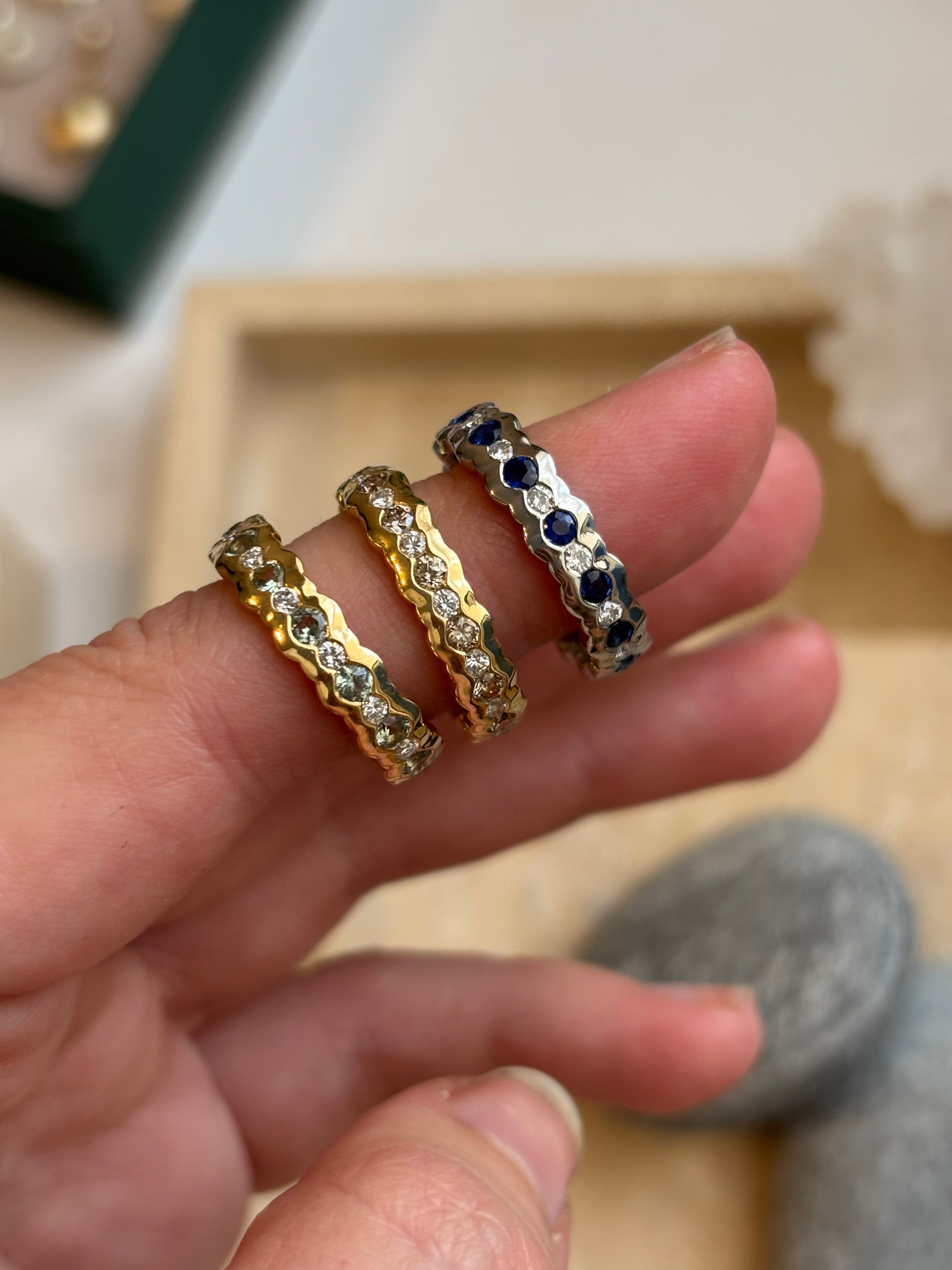 Eternity rings collection of sapphire and diamond platinum gold eternity band rings showing wavy design and gemstone detail