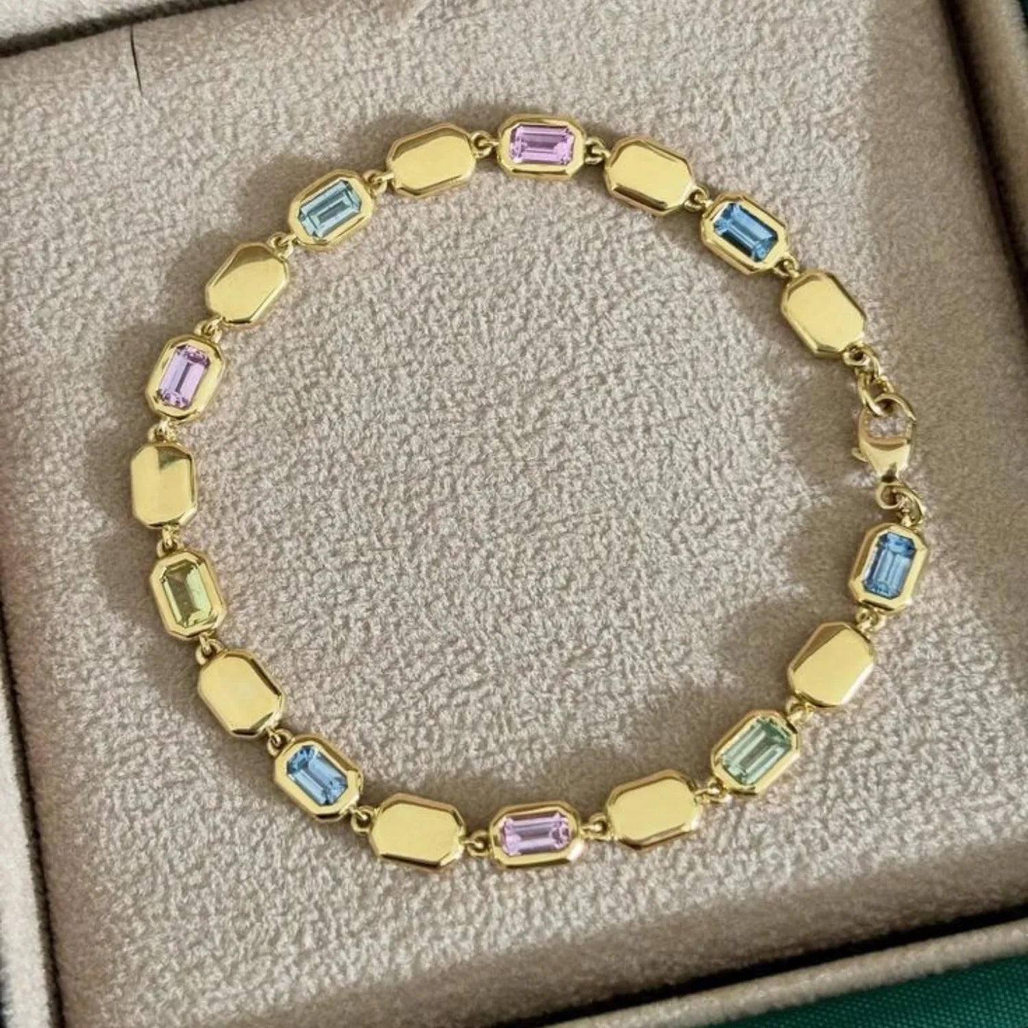 Close-up of Ley Lines Sapphire Bracelet showing nine pastel sapphires in blue, green, and pink set in 18k yellow gold