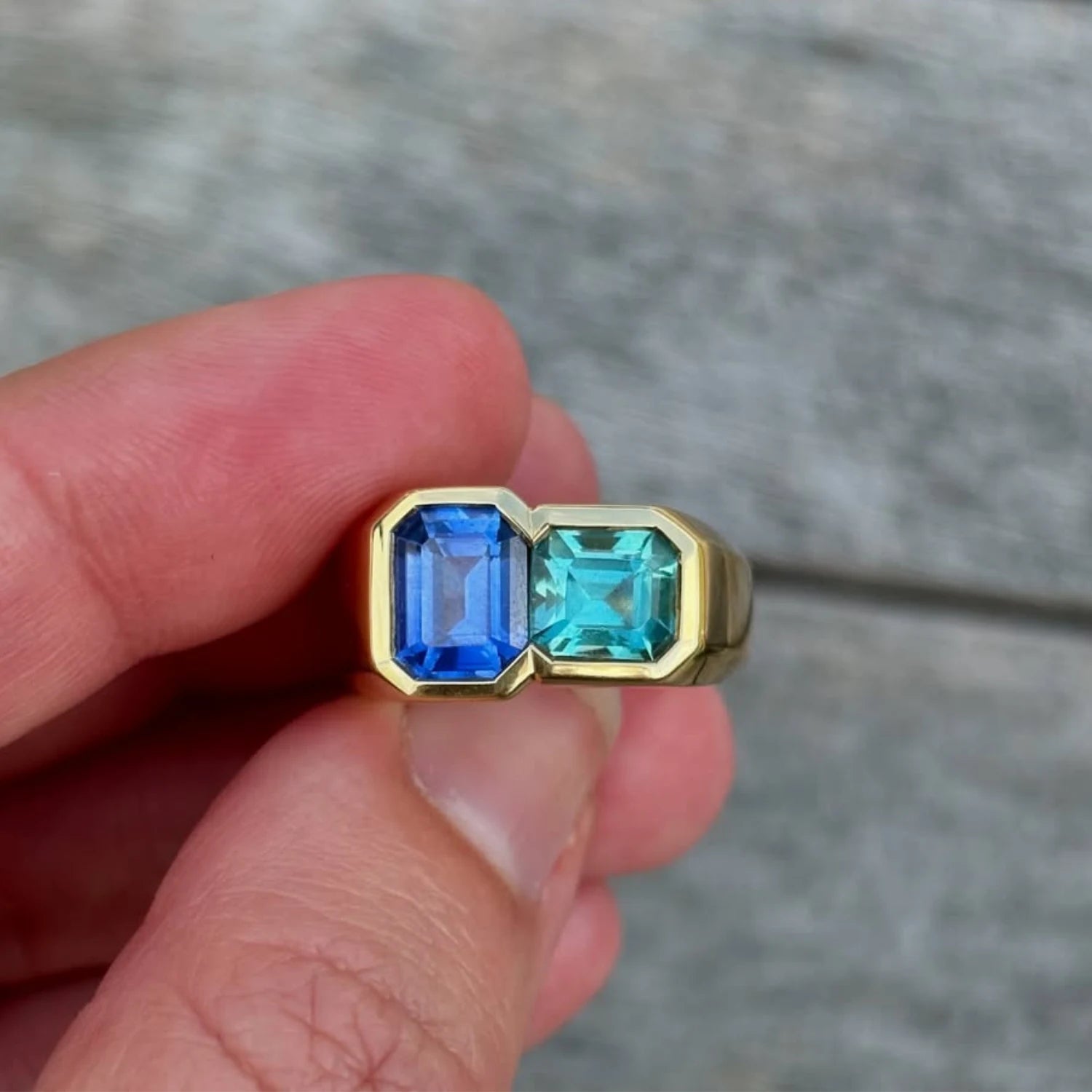 Close-up of Toi et Moi ring with geometric-cut sapphire and vibrant tourmaline set in 18k yellow gold inside minkajewels jewellery box