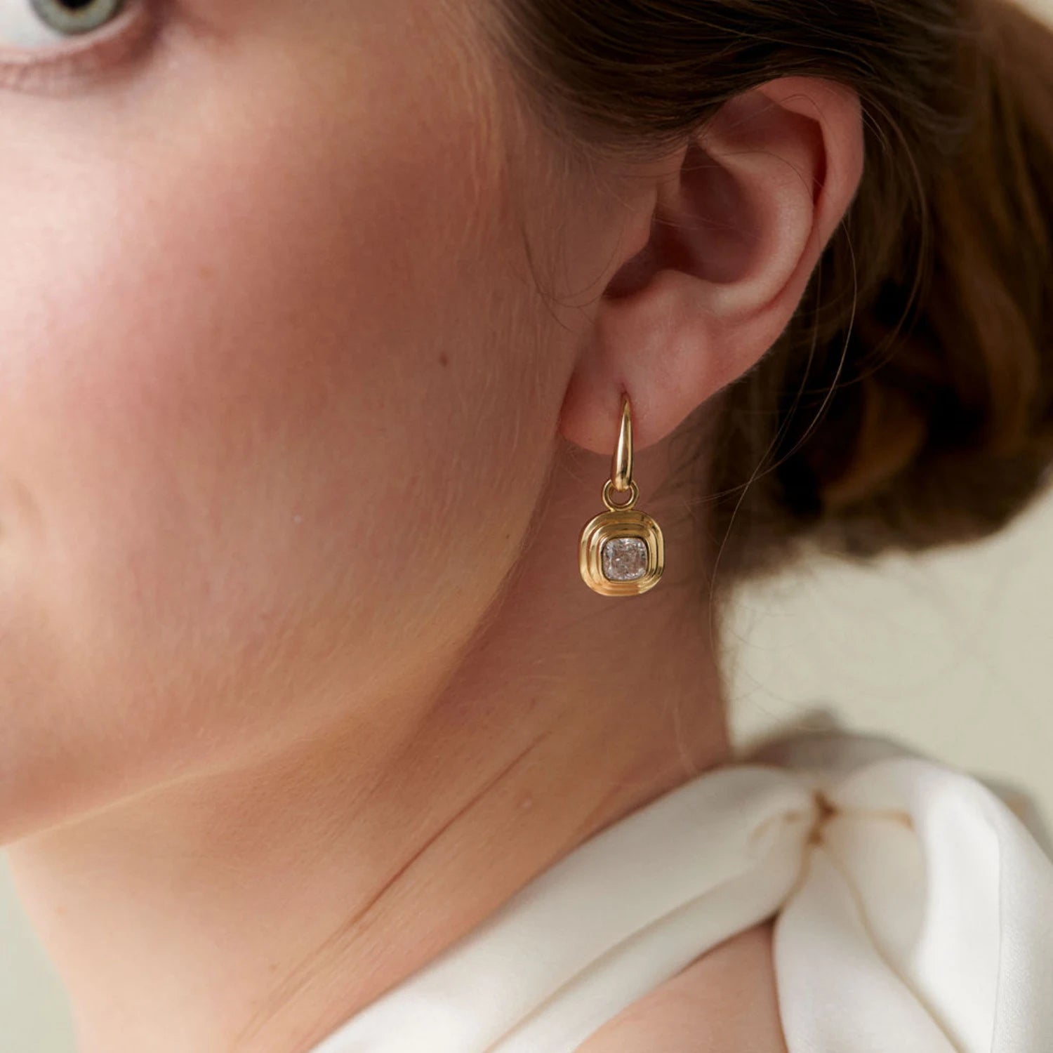 Close-up of Athena cushion-cut diamond earrings in 18k yellow gold with 1.20ct total diamonds and step detailing