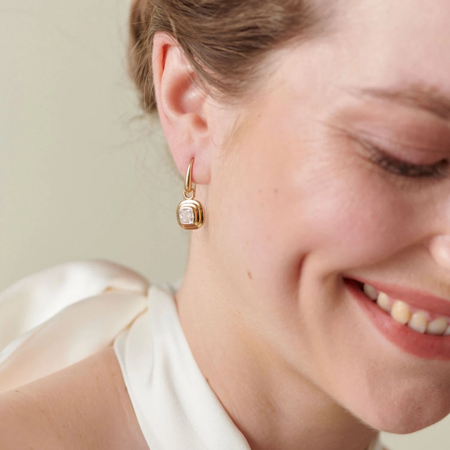 Model wearing Athena cushion-cut diamond earrings in 18k yellow gold with 1.20ct total diamonds and step detailing