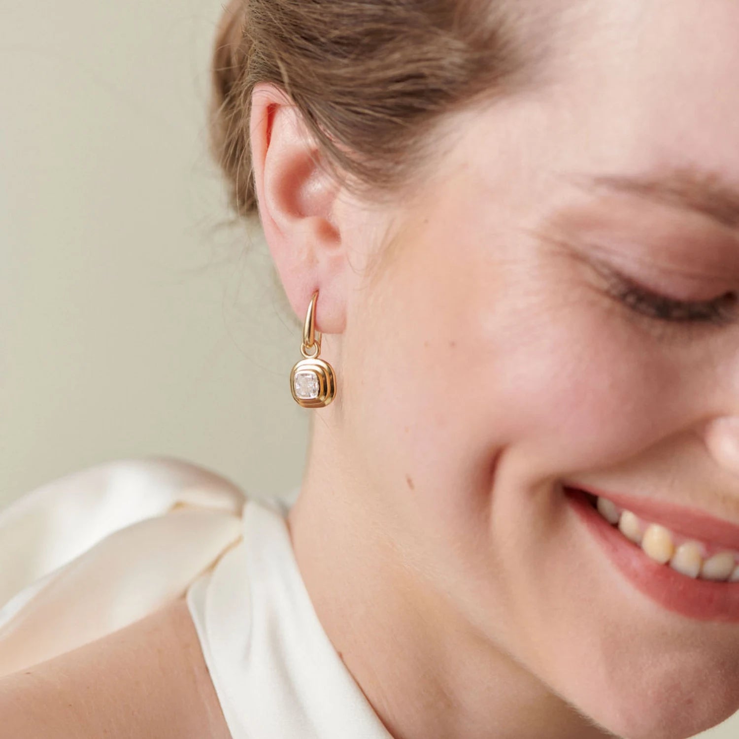 Model wearing Athena cushion-cut diamond earrings in 18k yellow gold with 1.20ct total diamonds and step detailing