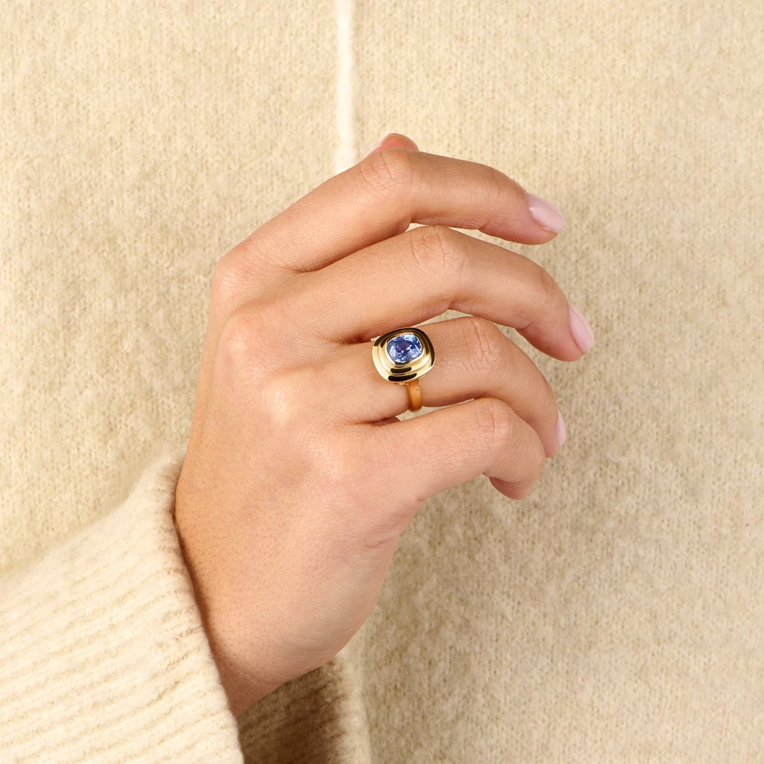Model hand wearing Athena antique cushion-cut blue sapphire ring in 18k yellow gold with richly coloured sapphire