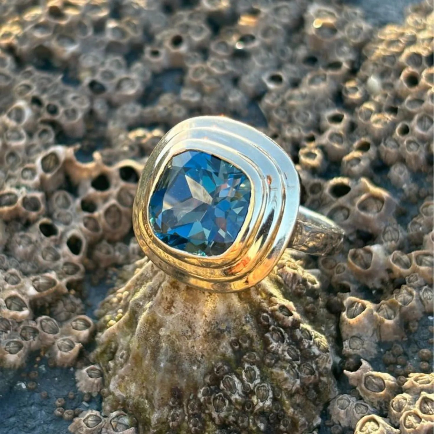Close-up of Athena 4ct London blue topaz ring in 14k yellow gold with sterling silver band featuring cushion-cut deep blue topaz