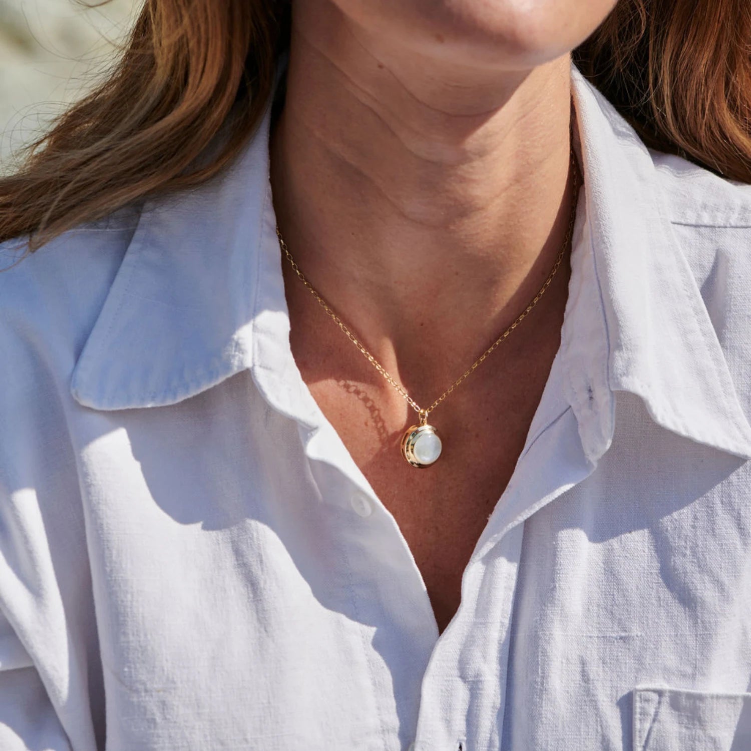 Close-up of Athena mother of pearl necklace in 14k yellow gold with iridescent pendant and step detailing
