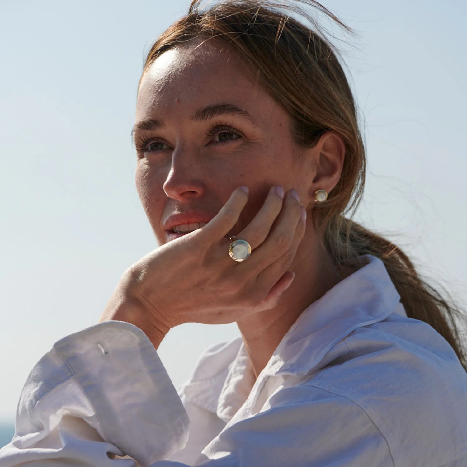 Close-up of Athena mother of pearl stud earrings in 14k yellow gold with iridescent gemstones and step detailing