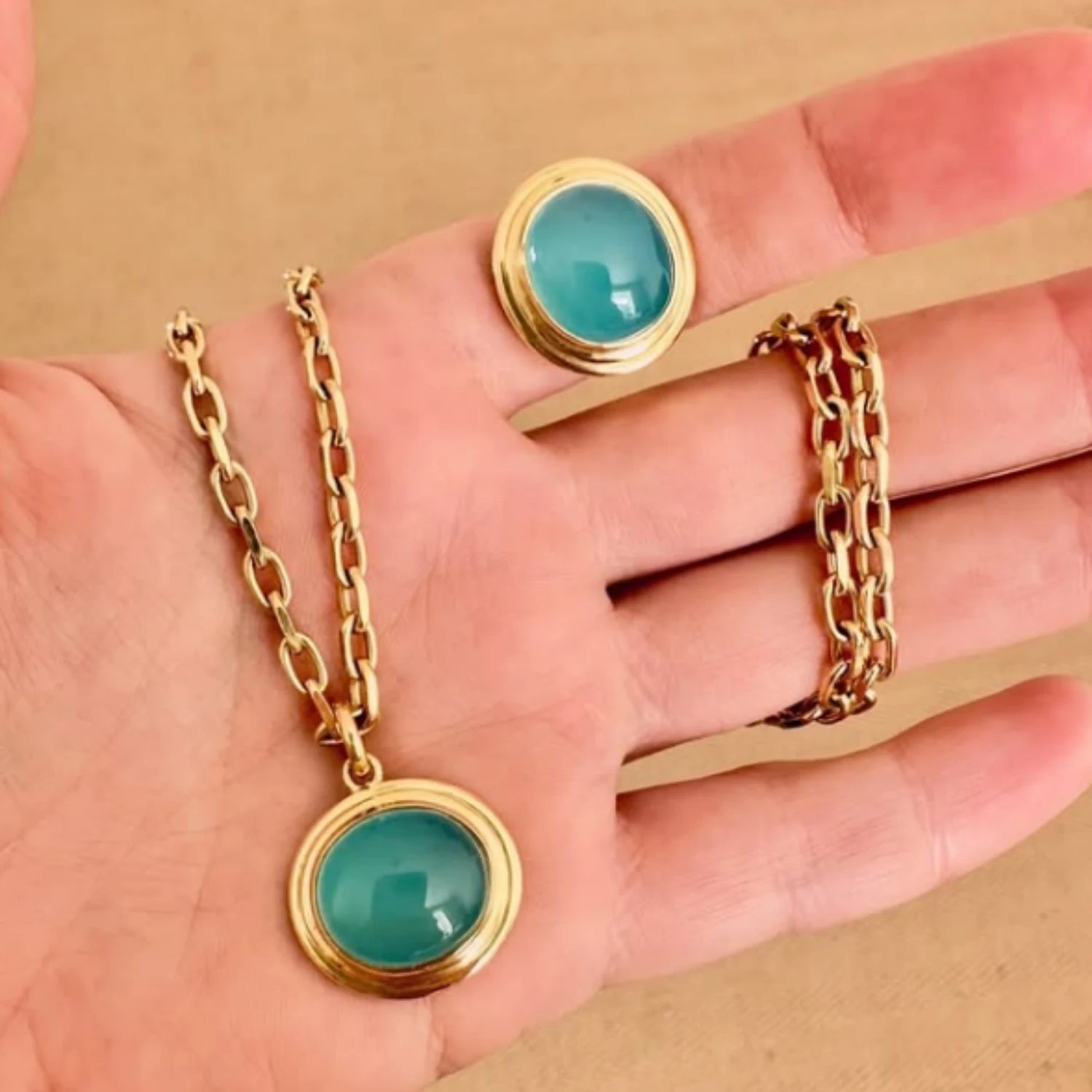 Close-up of Athena sea blue chalcedony cabochon pendant in 18k yellow gold featuring 14x12mm luminous gemstone on minkajewels chunky chain