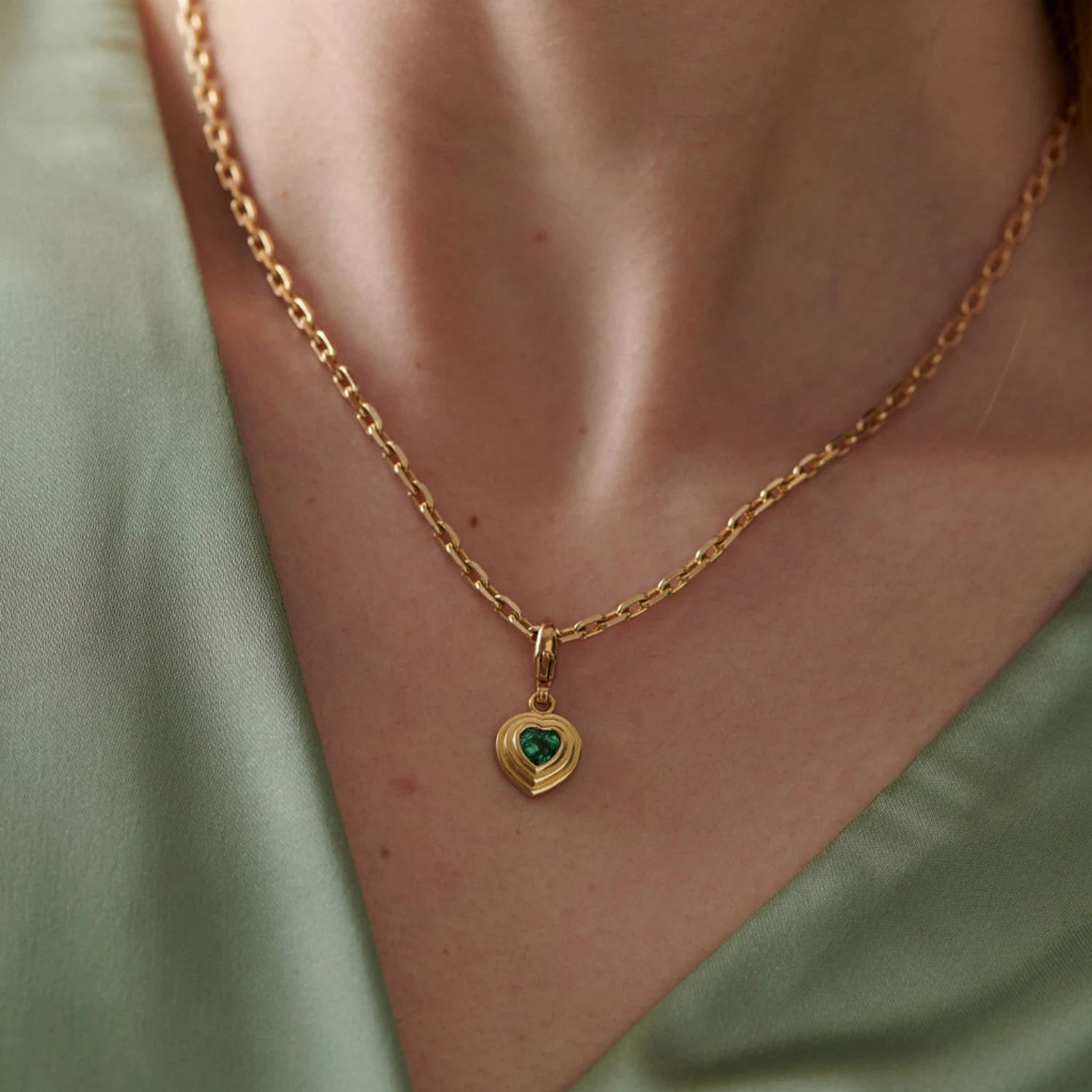 Model wearing Athena tourmaline heart charm in 18k yellow gold on chain featuring heart-shaped gemstone with step detailing