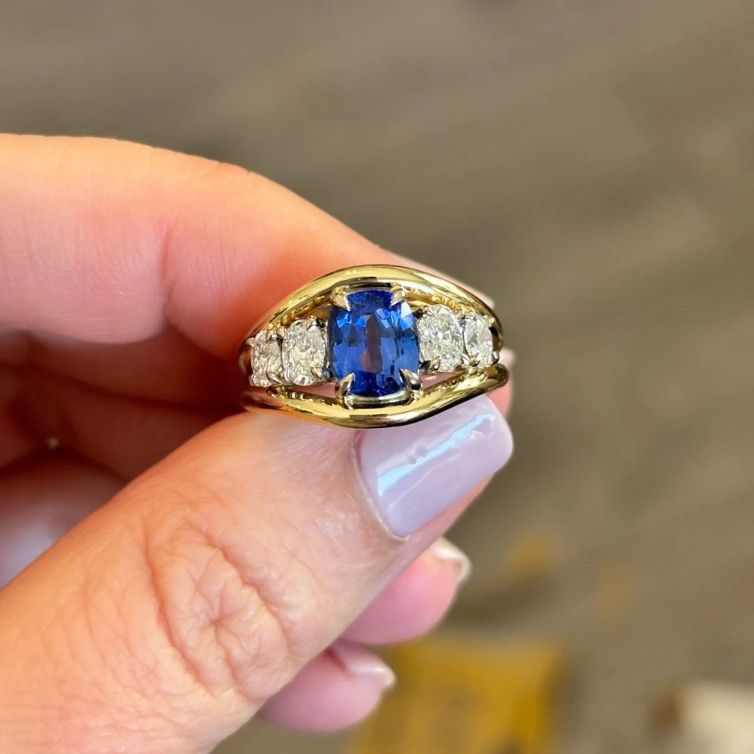 Close-up of Atlantis mermaid ring featuring 3.04ct GIA-certified royal blue sapphire surrounded by oval-cut white diamonds in 18k yellow gold