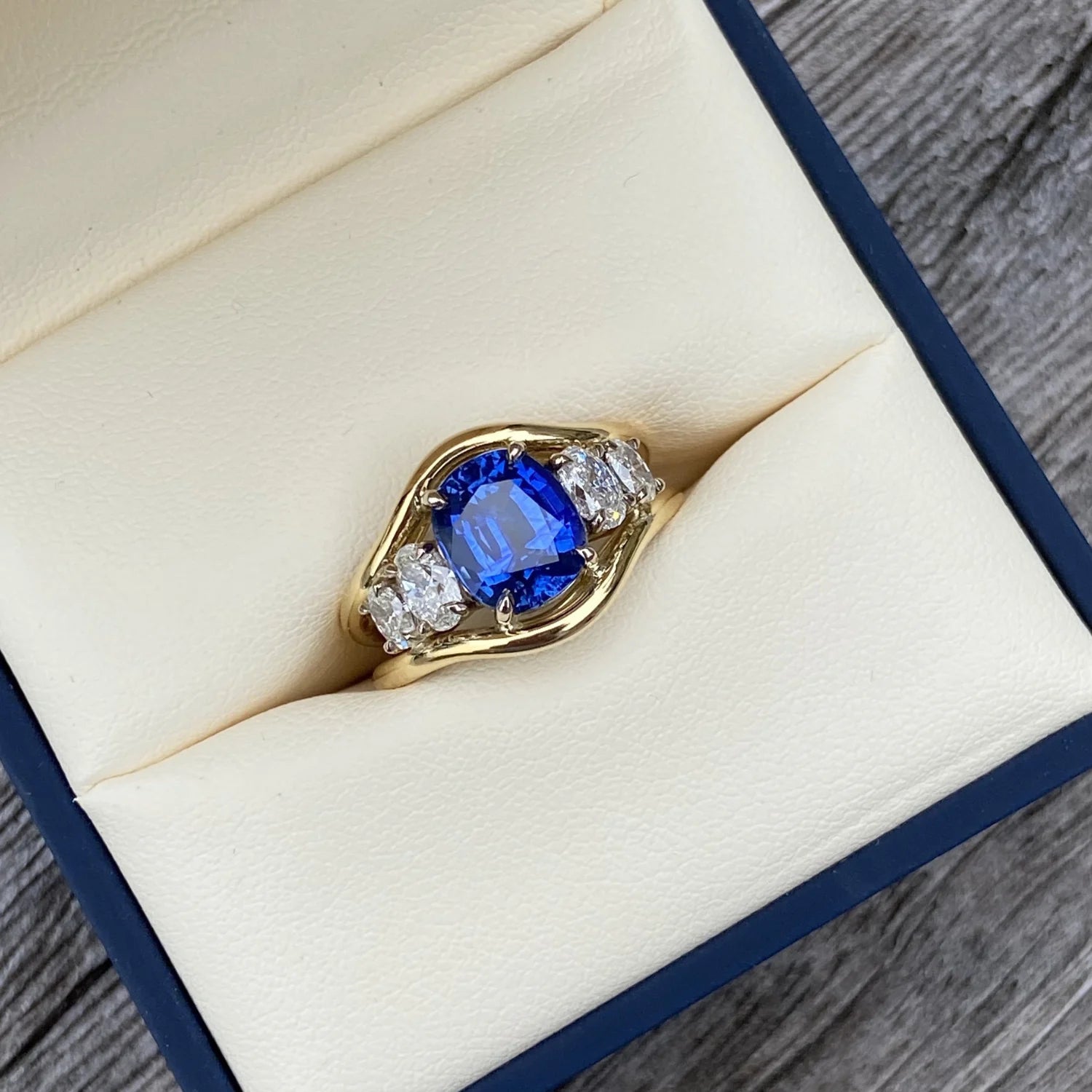 Atlantis 3.04ct sapphire and diamond mermaid ring in 18k yellow gold displayed in jewellery box with royal blue sapphire and oval diamonds.