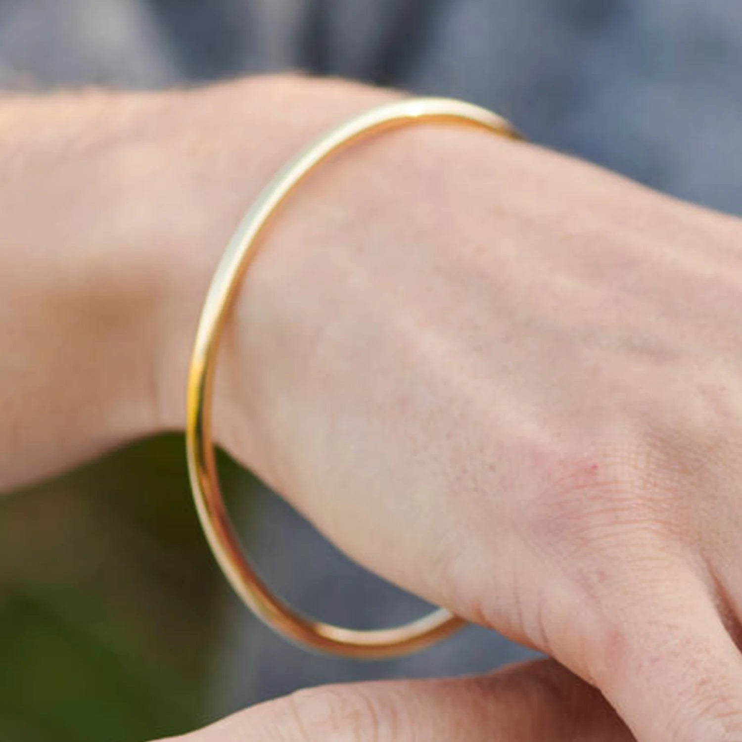 Model wearing 3mm gold mermaid bracelet in solid 18k yellow gold with delicate round bangle design
