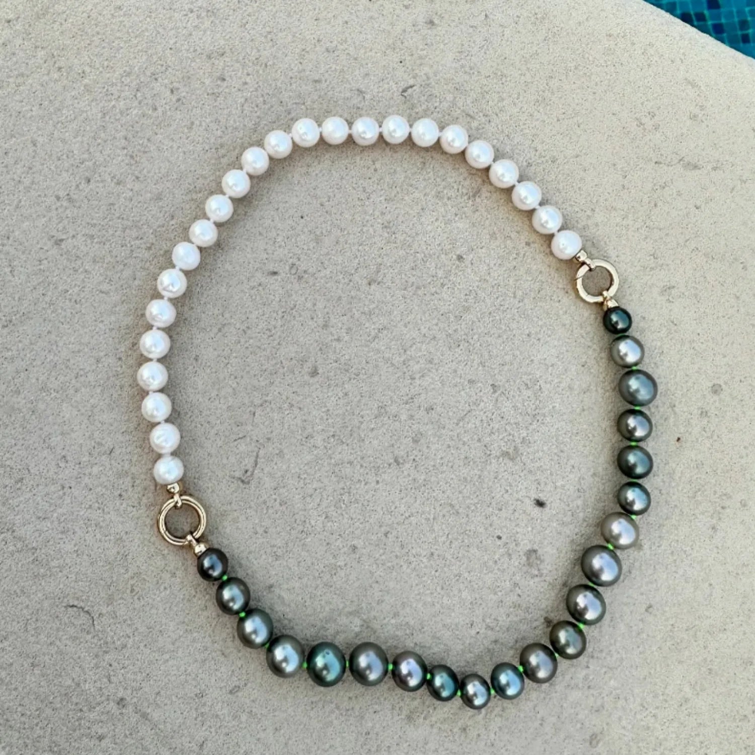 Close-up of Atlantis Pearl Necklace in 18k yellow gold with stormy black Tahitian pearls and white freshwater pearls hand-knotted on neon green thread