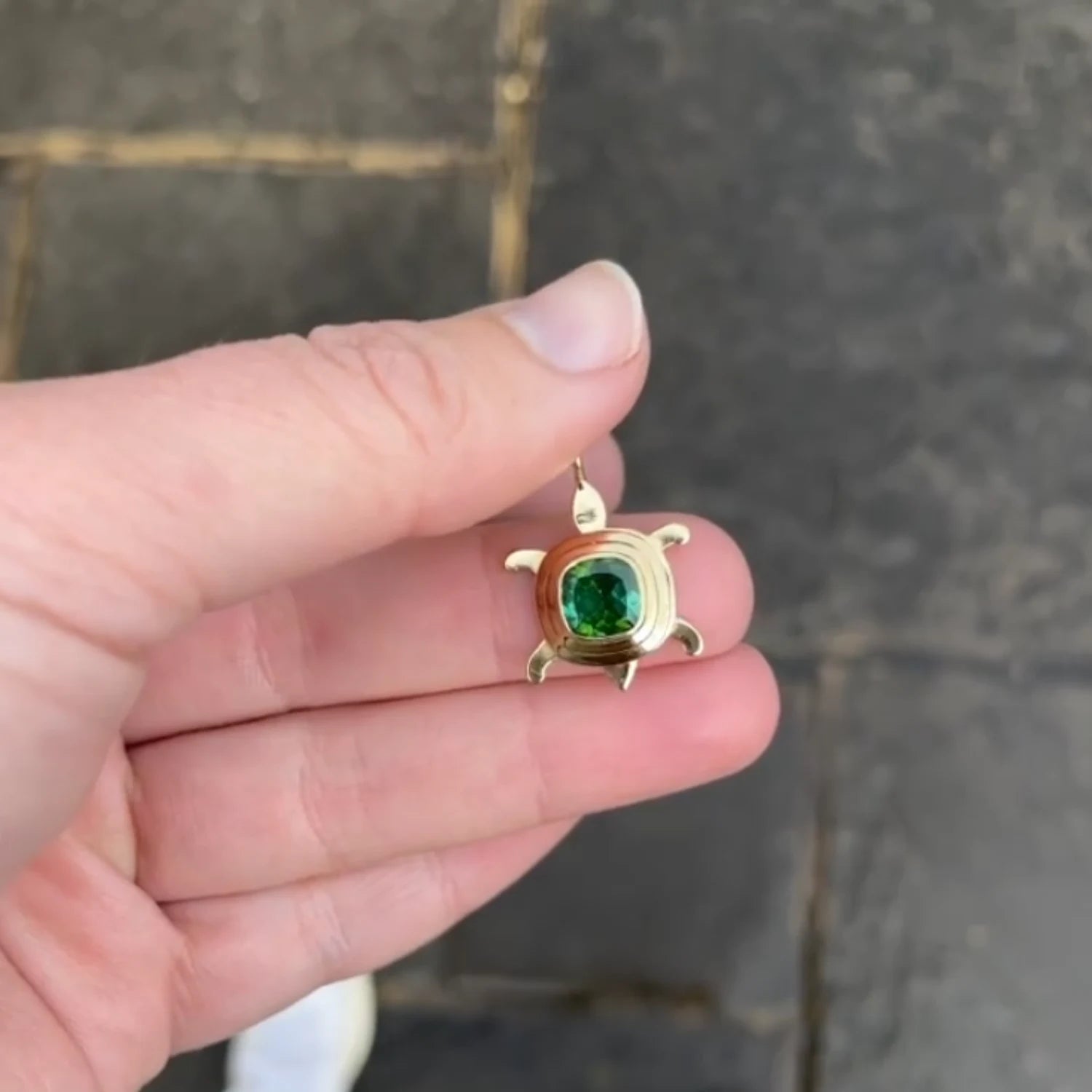 Close-up of Atlantis dancing turtle tourmaline charm in solid 18k yellow gold with vibrant tourmaline and articulated design