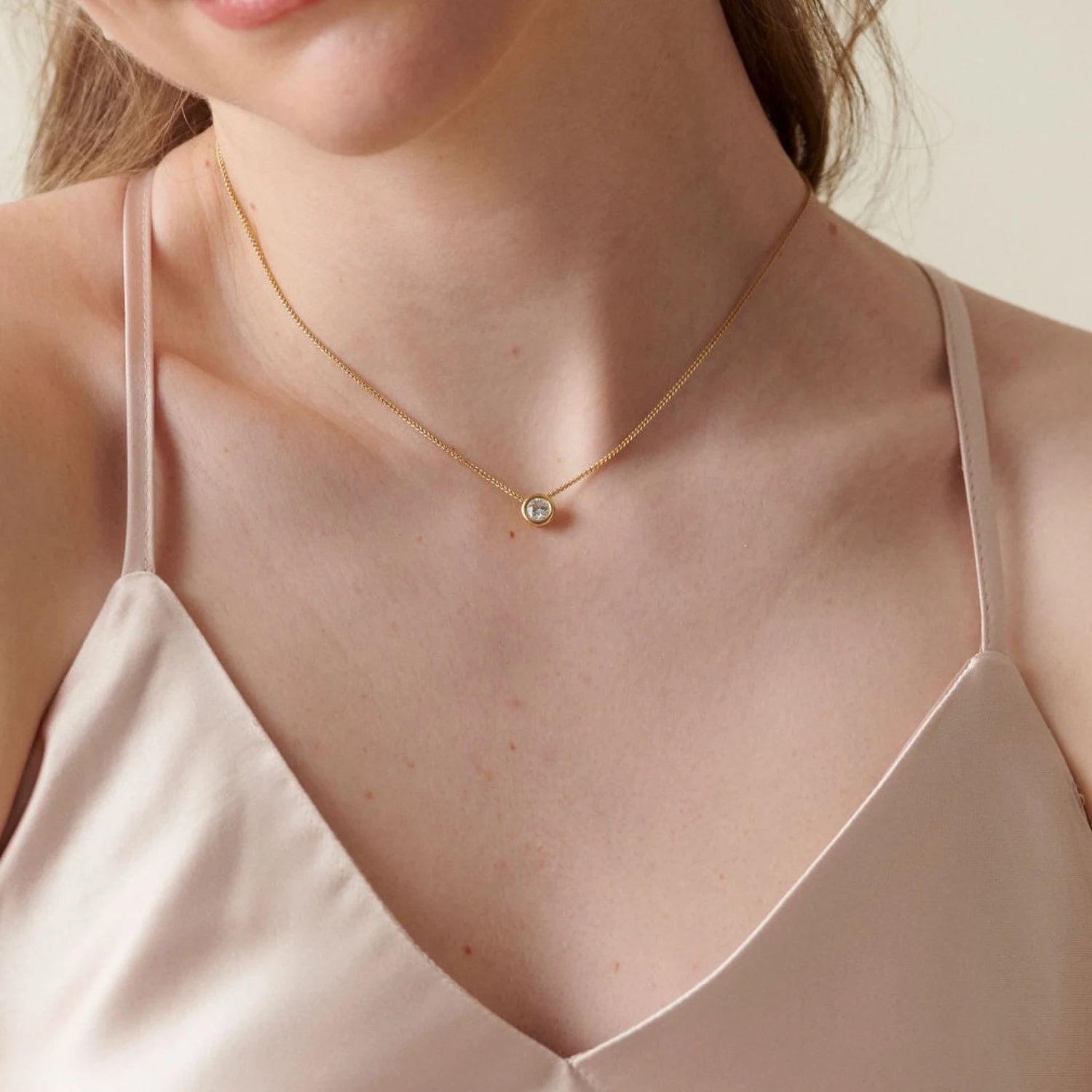 Model wearing Atlantis Diamond Solitaire Necklace in 18k yellow gold with 0.50ct round brilliant-cut diamond