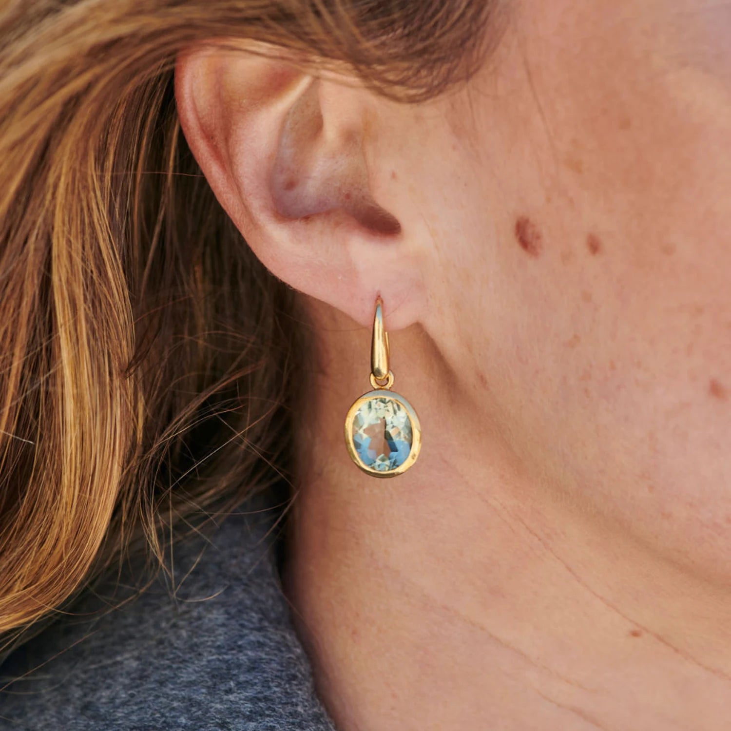 Close-up of green amethyst drop earrings showing 12 x 10mm stones set in 18k yellow gold