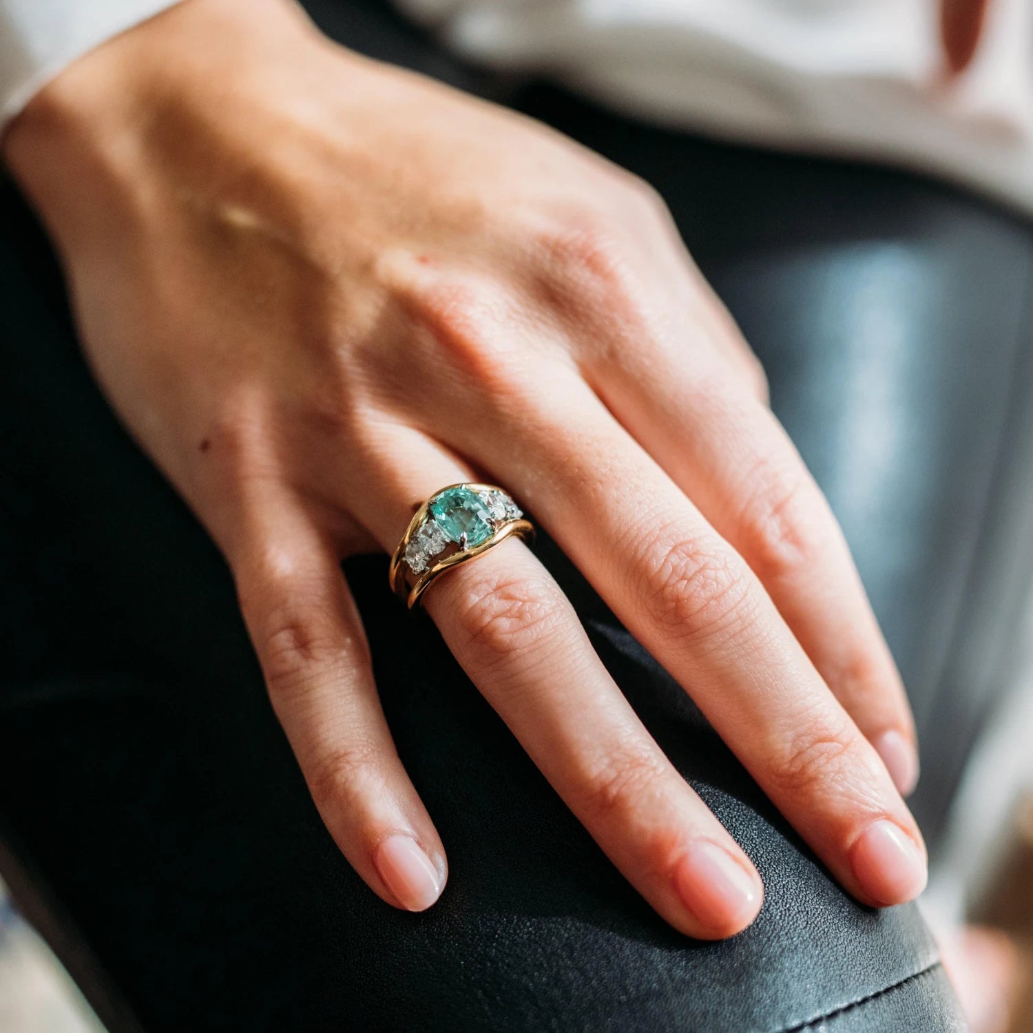 Close-up of Atlantis ring showing green tourmaline center stone with four oval-cut white diamonds in 18k yellow gold