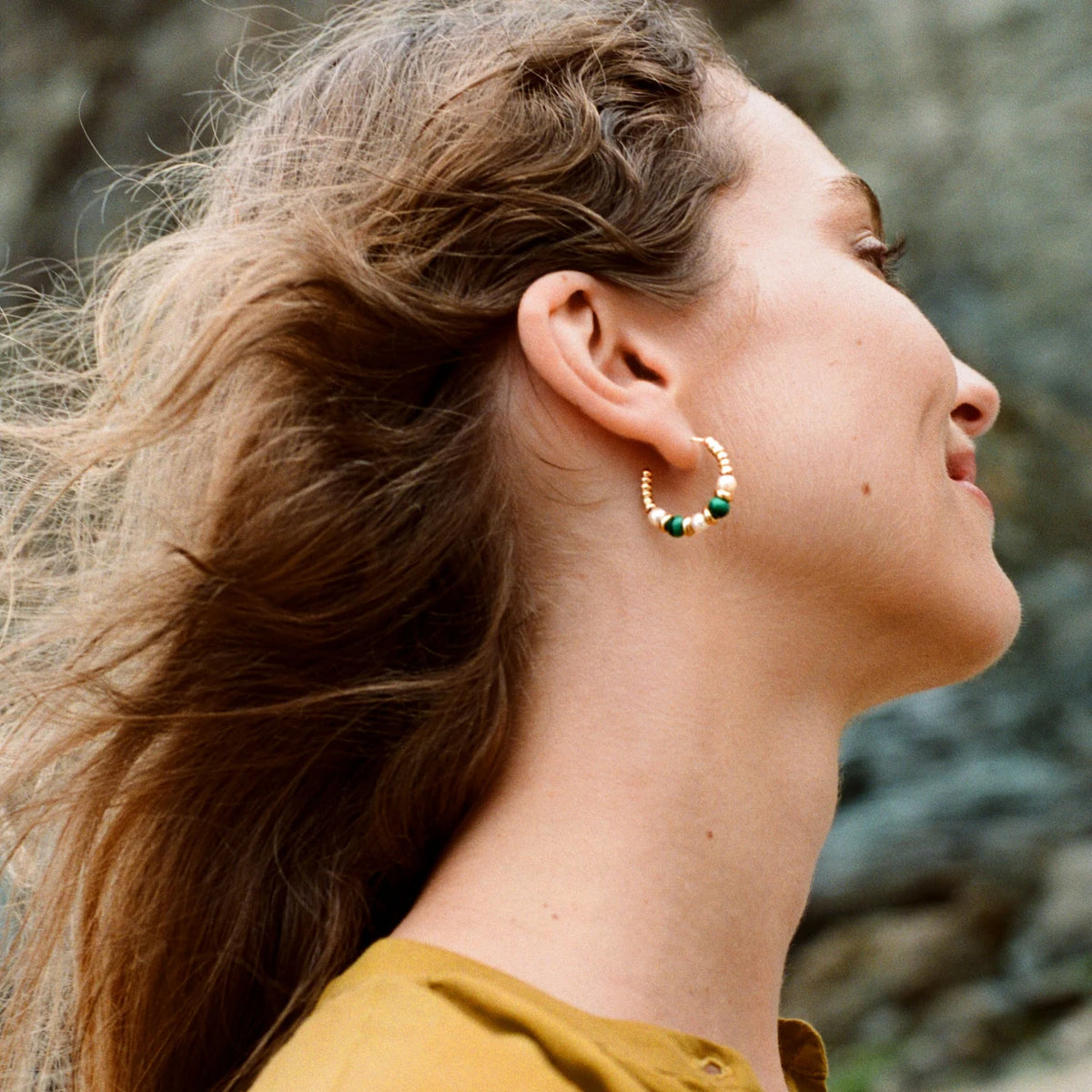 Model wearing 25mm Mermaid collection hoop earrings in 18k yellow gold with malachite and white pearls