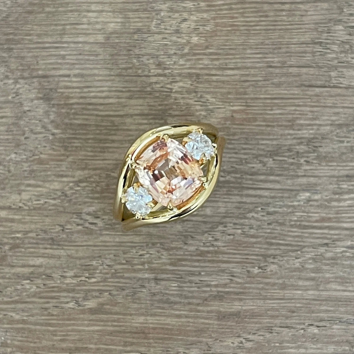 Close-up of Atlantis padparadscha sapphire mermaid ring in 18k yellow gold with square cushion-cut sapphire and round white diamonds