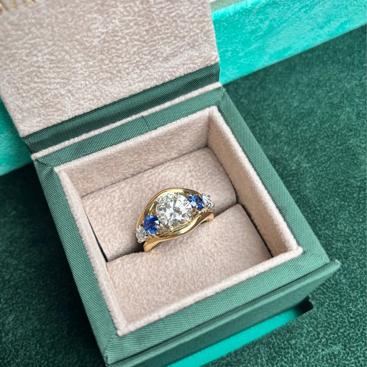 Close-up of Atlantis in 18k yellow gold mermaid band with trio round white diamonds and round sapphires