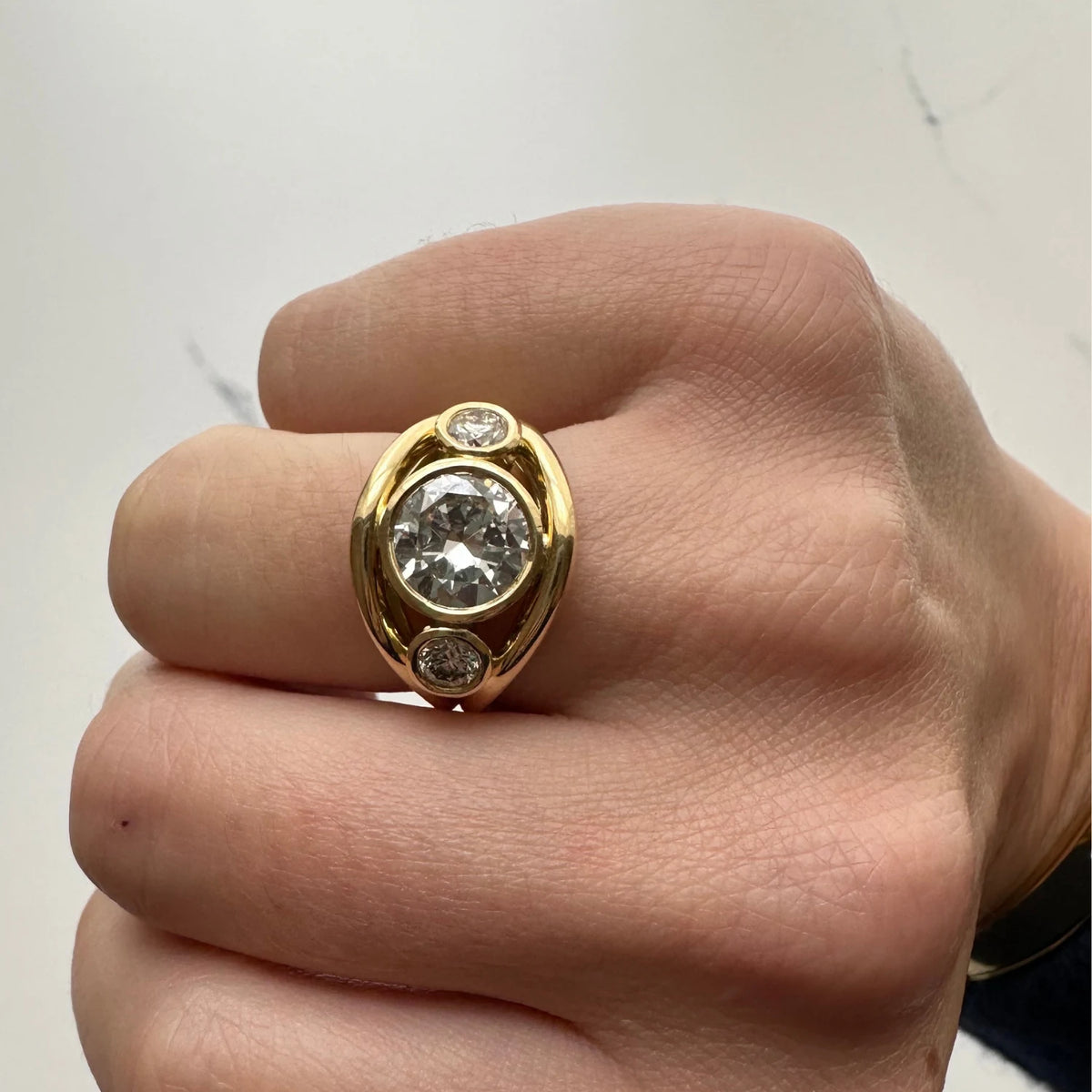 Close-up of Atlantis in 18k yellow gold double curved mermaid band with trio round white diamonds