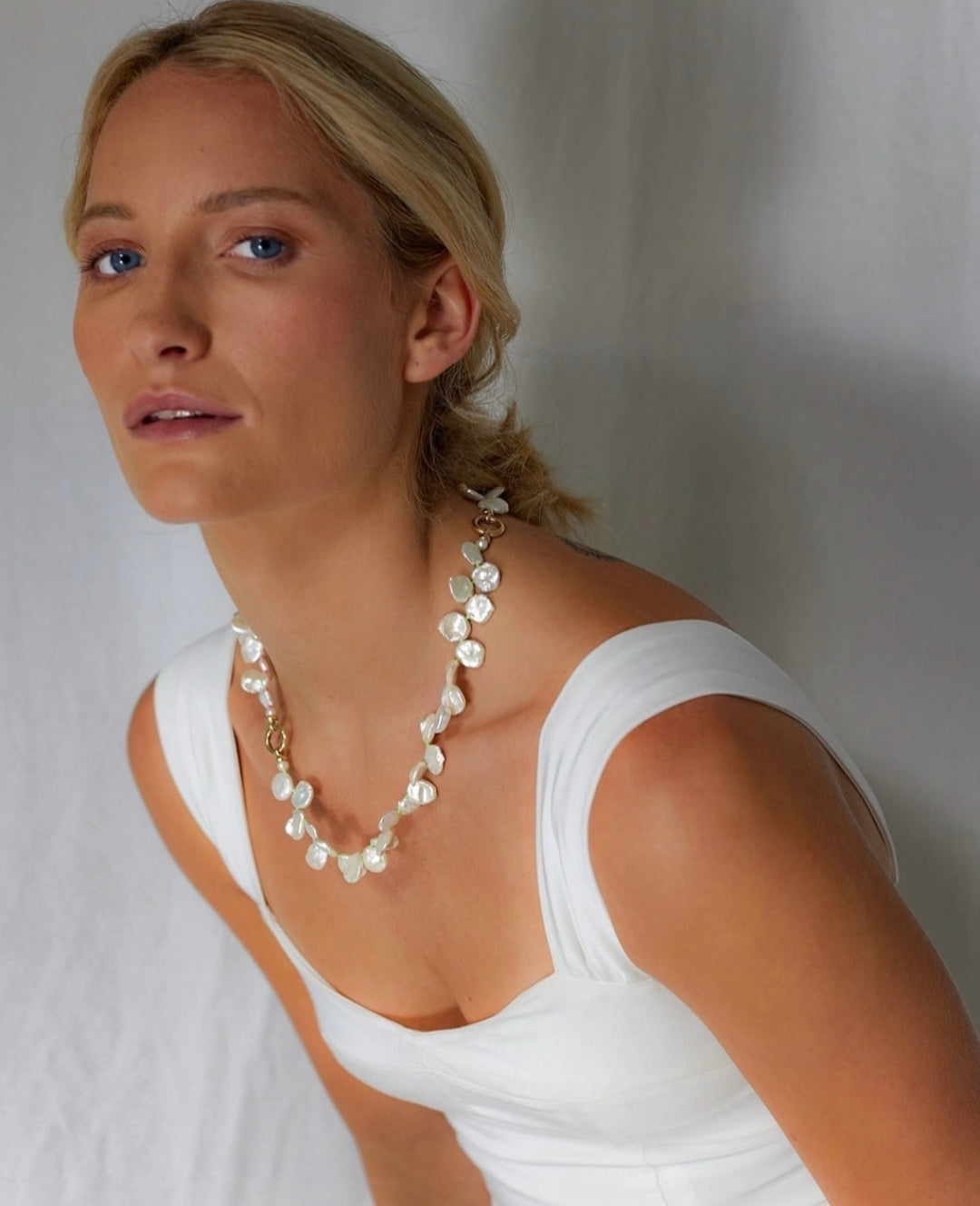 Model wearing Atlantis collection 18k yellow gold necklace featuring white Keshi pearls
