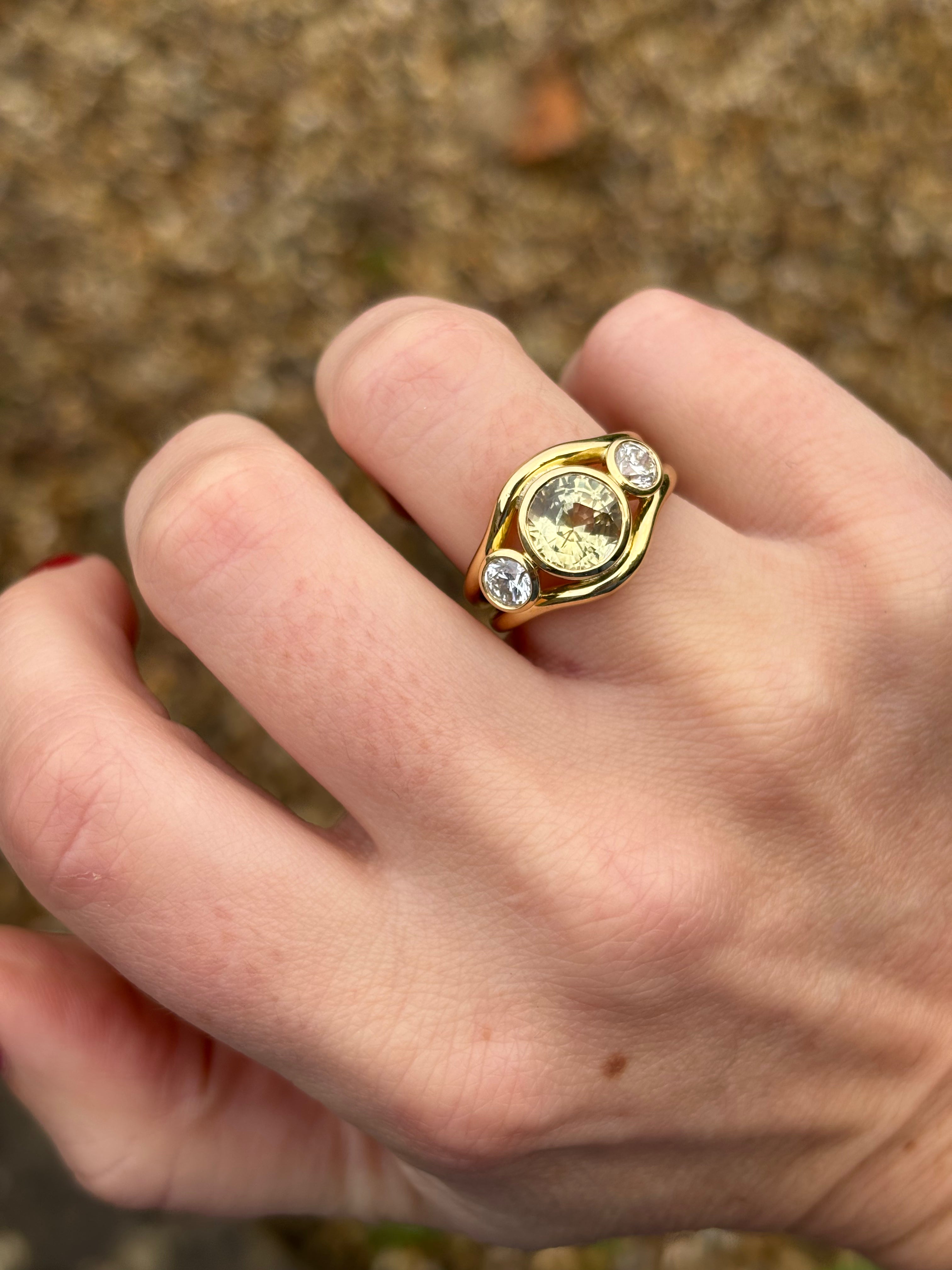 Close-up lifestyle image of untreated yellow sapphire and diamond Atlantis ring showing double curved band