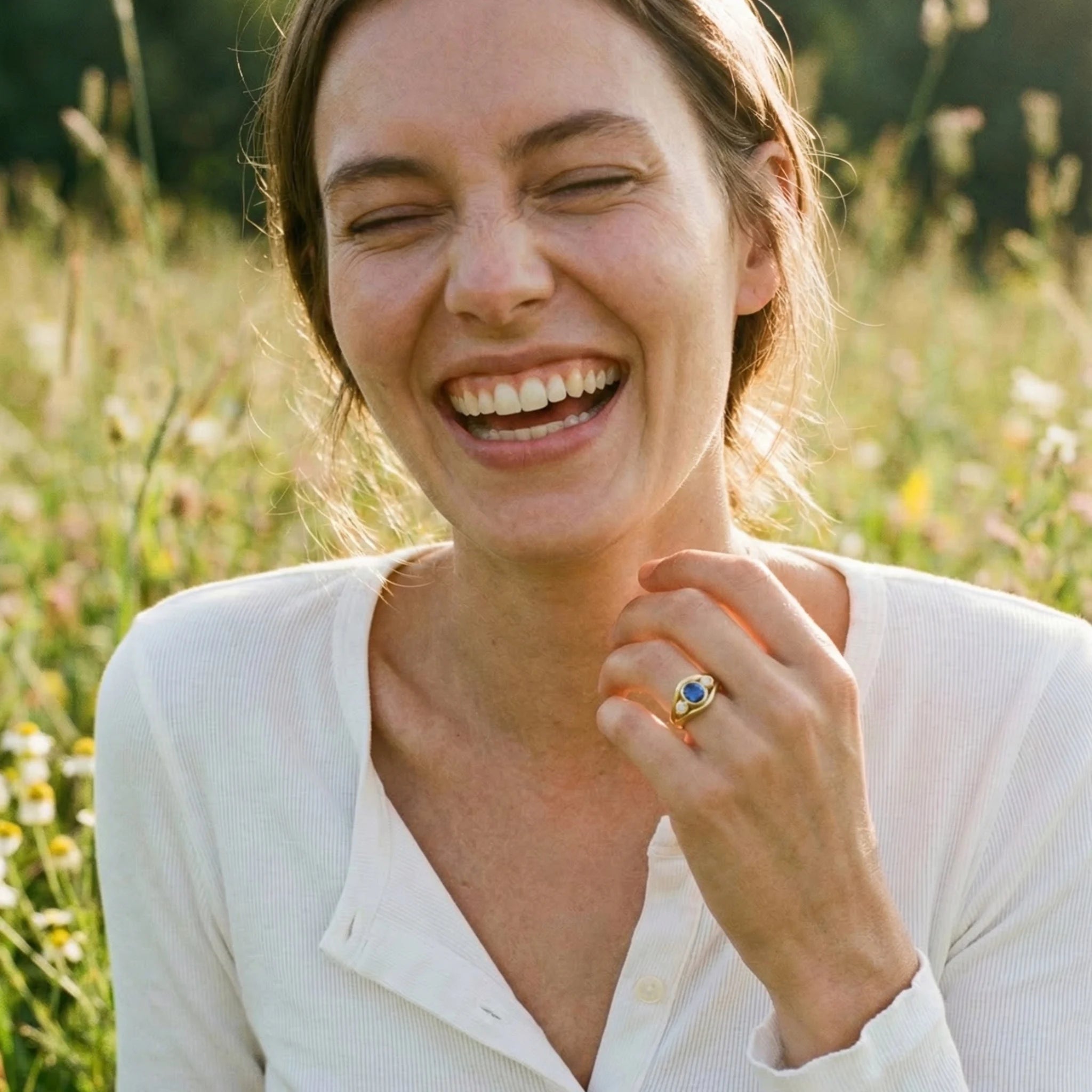 Blue sapphire and diamond Atlantis ring on model’s hand, showing mermaid-inspired double curved band