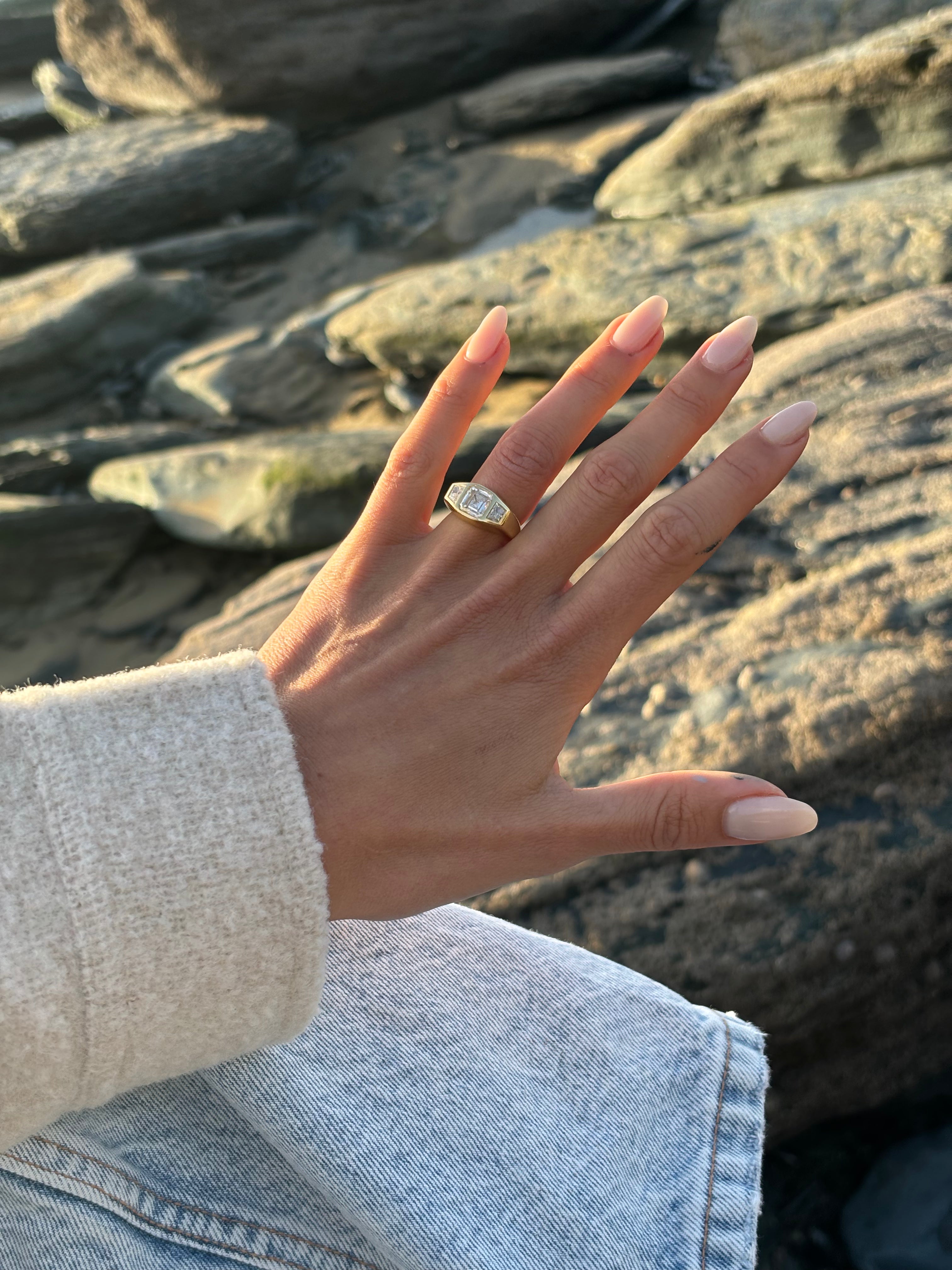 Hand model wearing 18k yellow gold engagement ring with 2ct octagon (Asscher) diamond and trapezoid diamonds