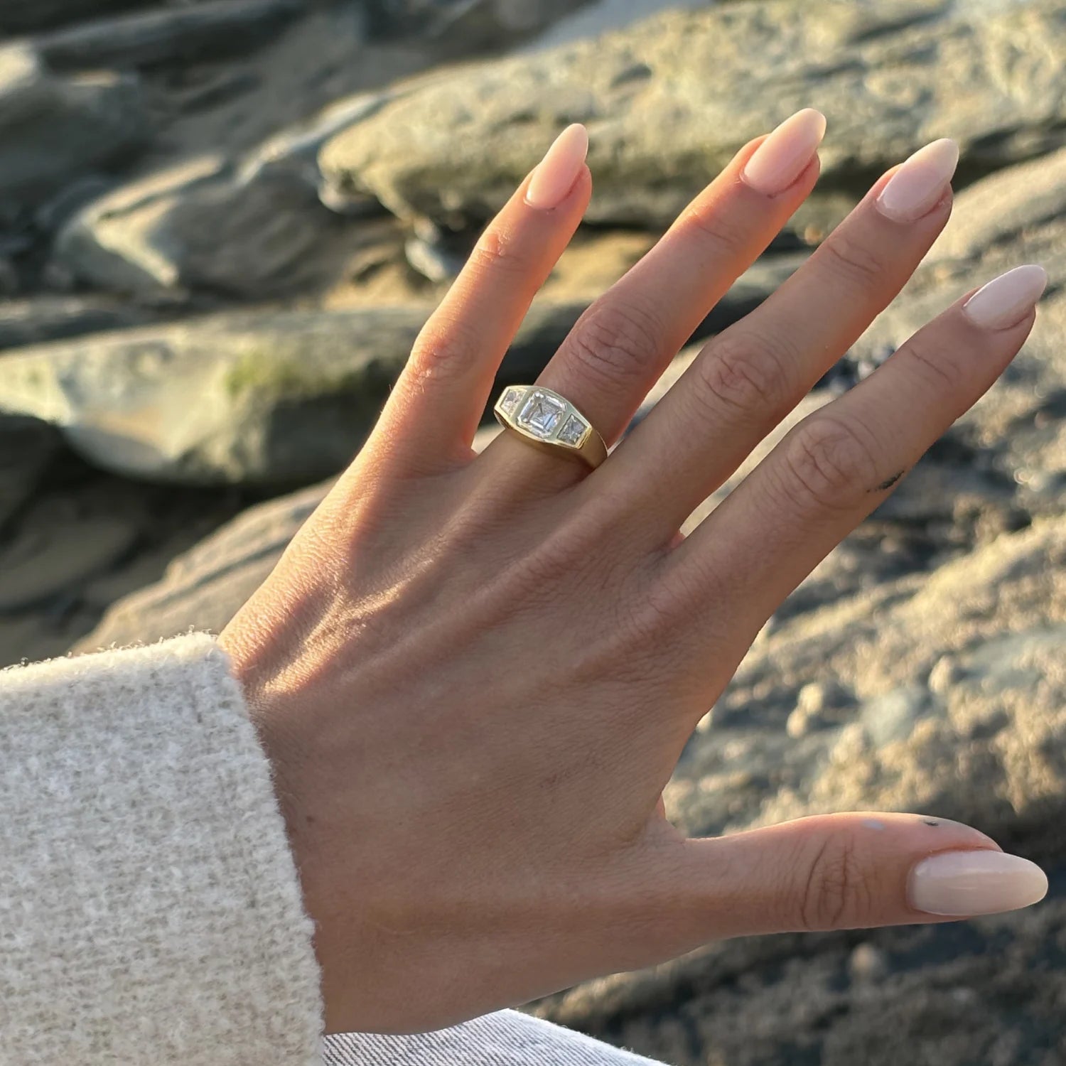 Hand wearing Asscher-cut diamond ring in 18k yellow gold with 2ct octagon center diamond and trapezoid side stones