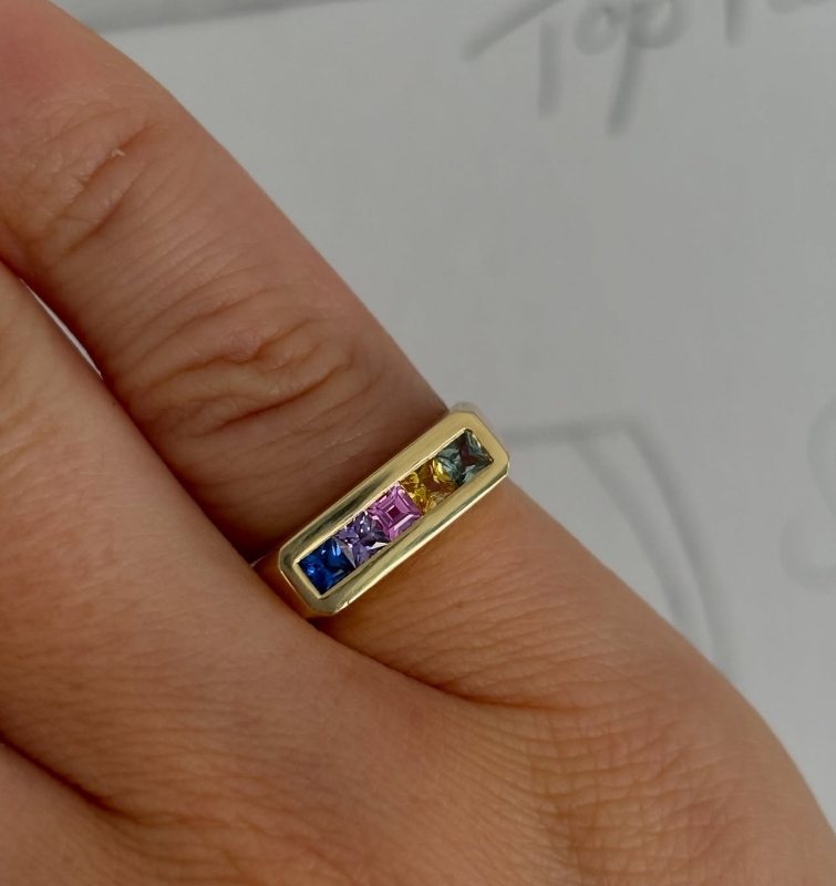 Close-up of rainbow sapphire Ley Lines pinky ring in 18k yellow gold showing princess-cut stones