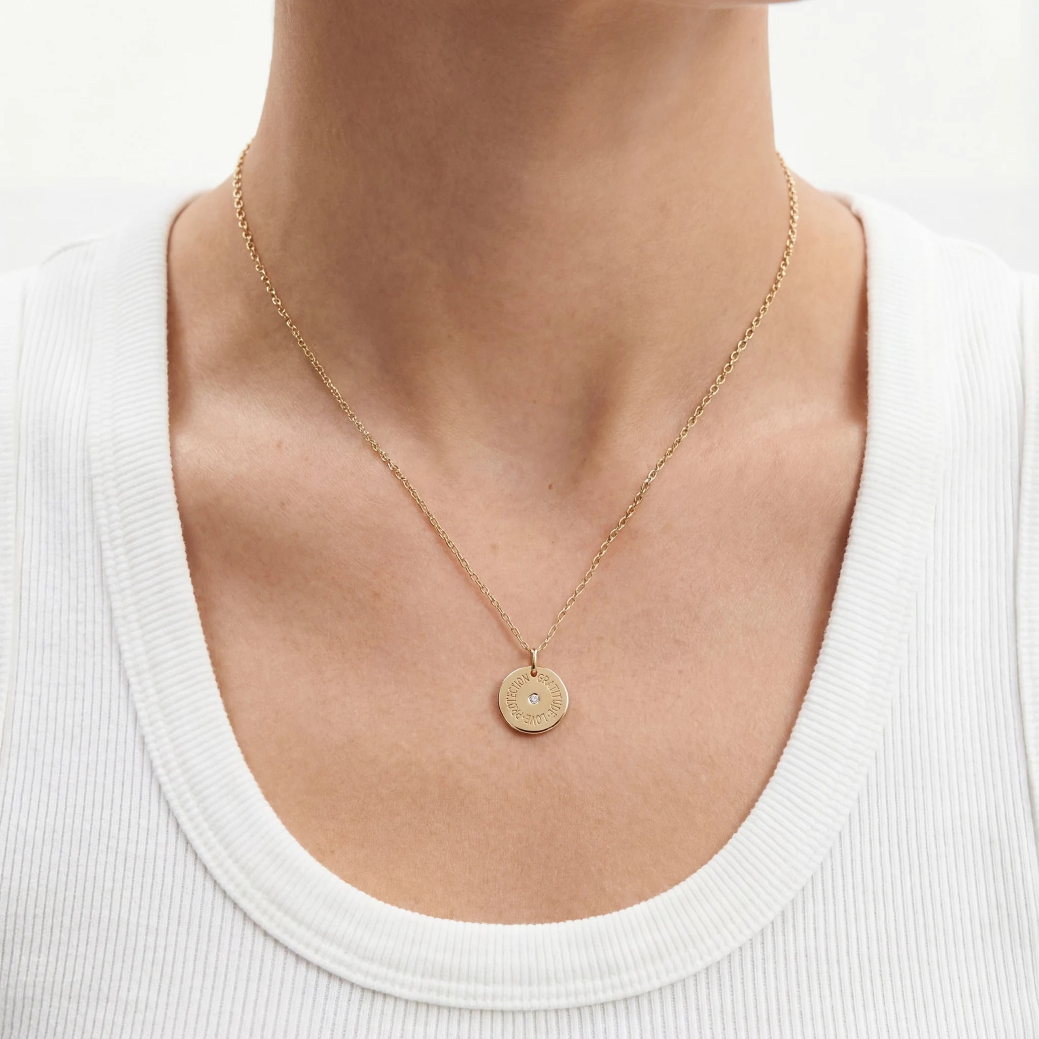 Close-up of 15mm engraved mantra disc pendant with central diamond, showing three words on the front and year on the reverse, oval jump ring for chain attachment